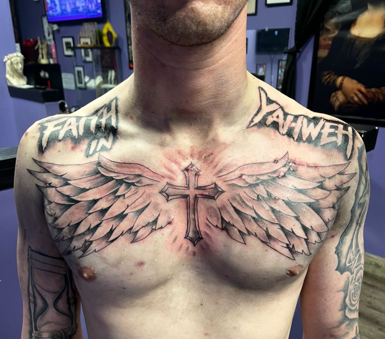 Cross with wings black and grey tattoo on the chest by Mark Calloway