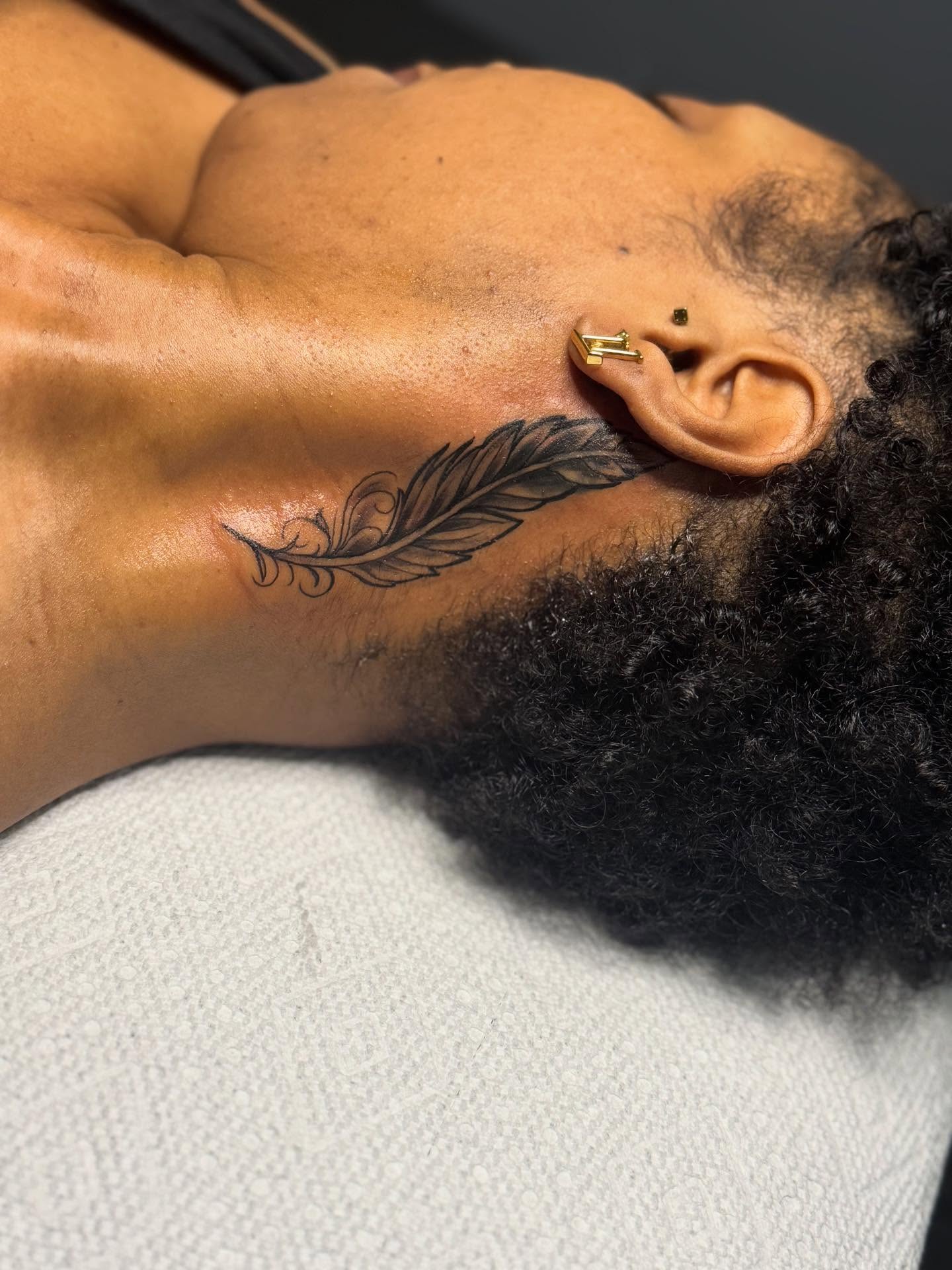Feather black and grey tattoo on the neck by Tattoosbydevon