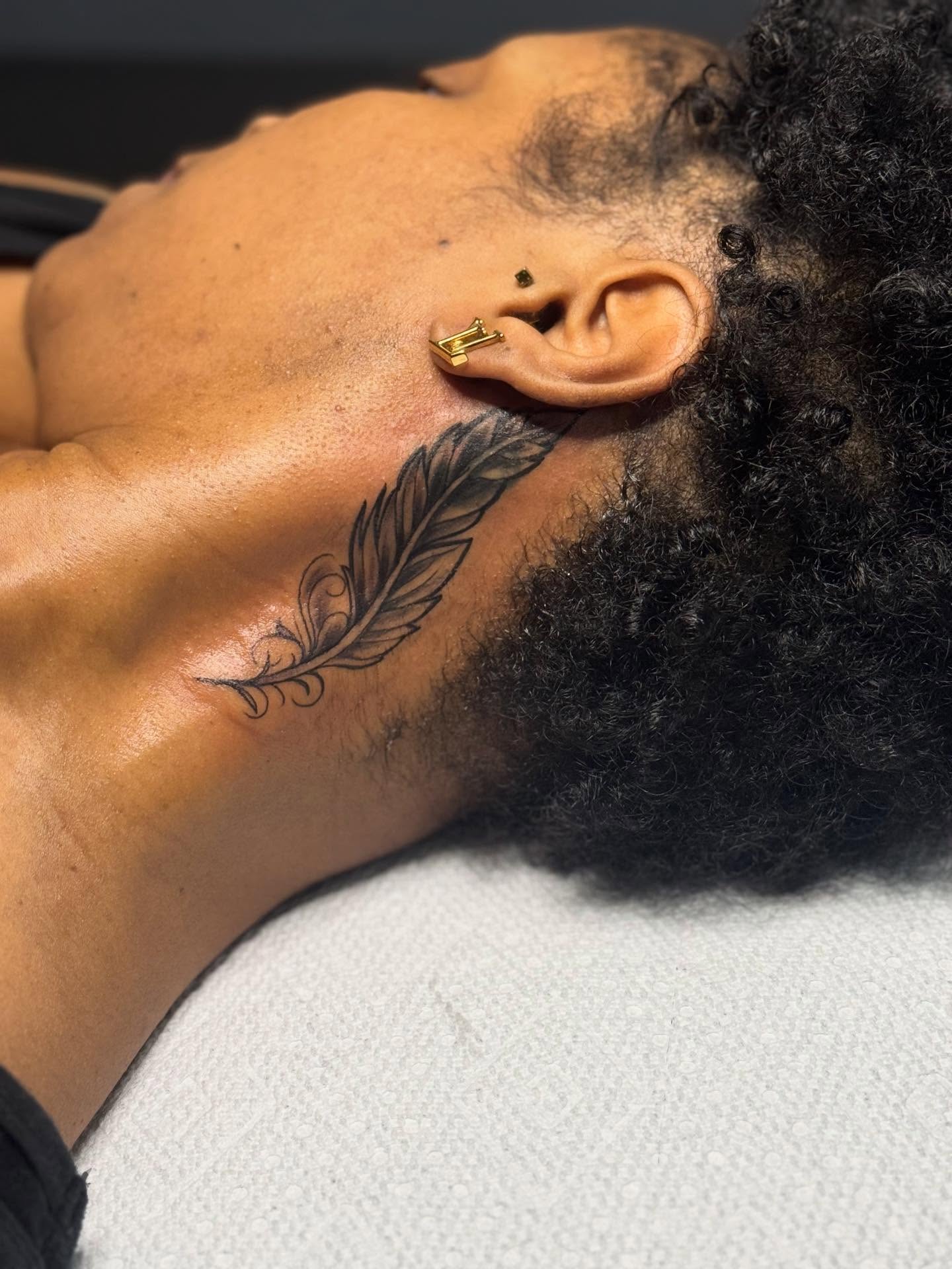 Feather black and grey tattoo on the neck by Tattoosbydevon