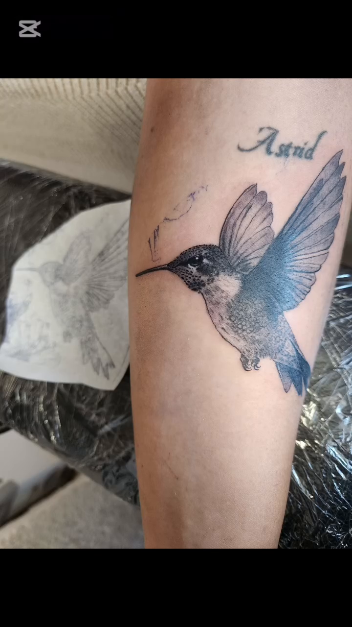 Hummingbird with name watercolor tattoo on the upper arm by Sonia