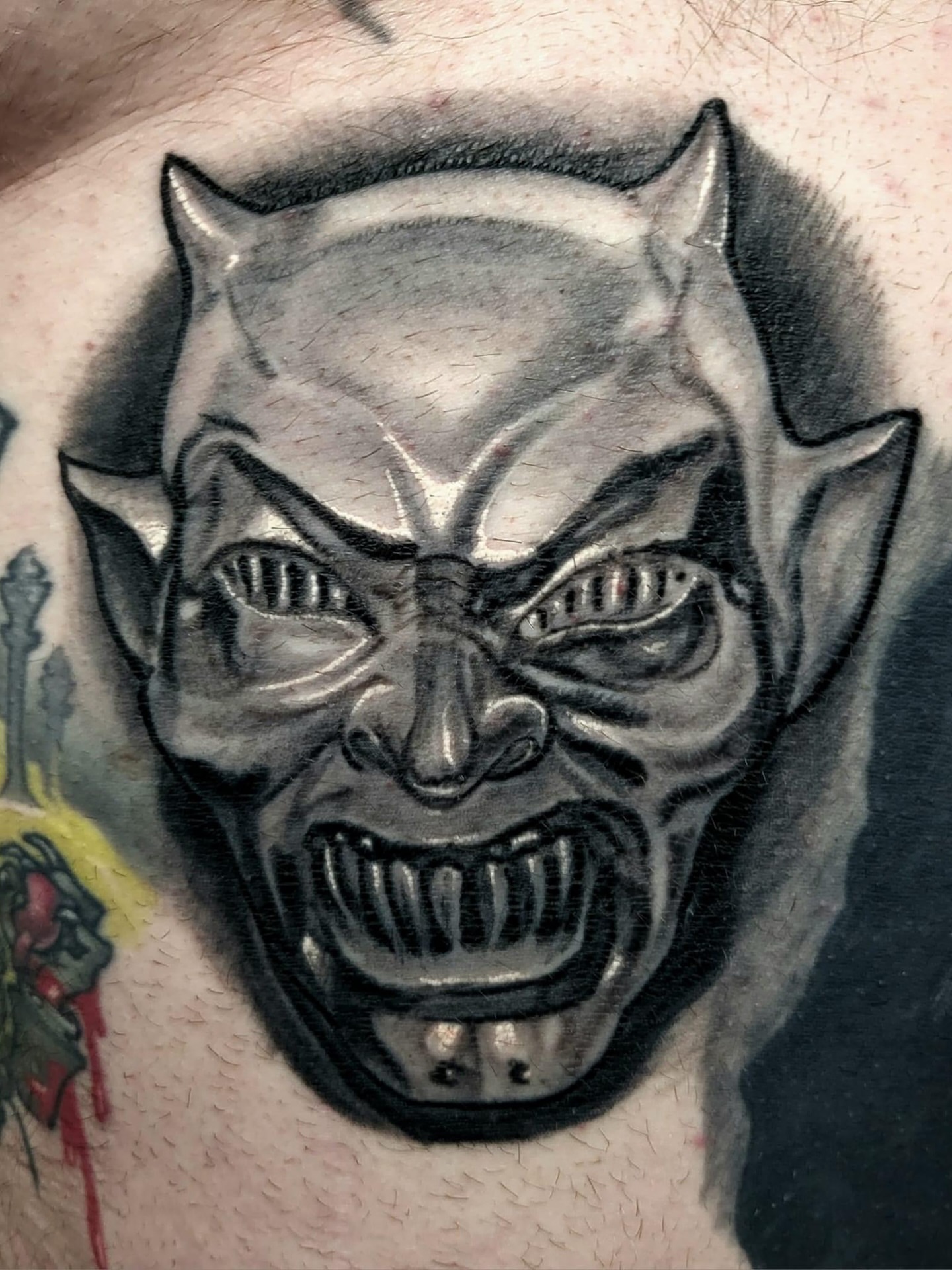Demon face dark realism tattoo on the chest by Edward Argibay