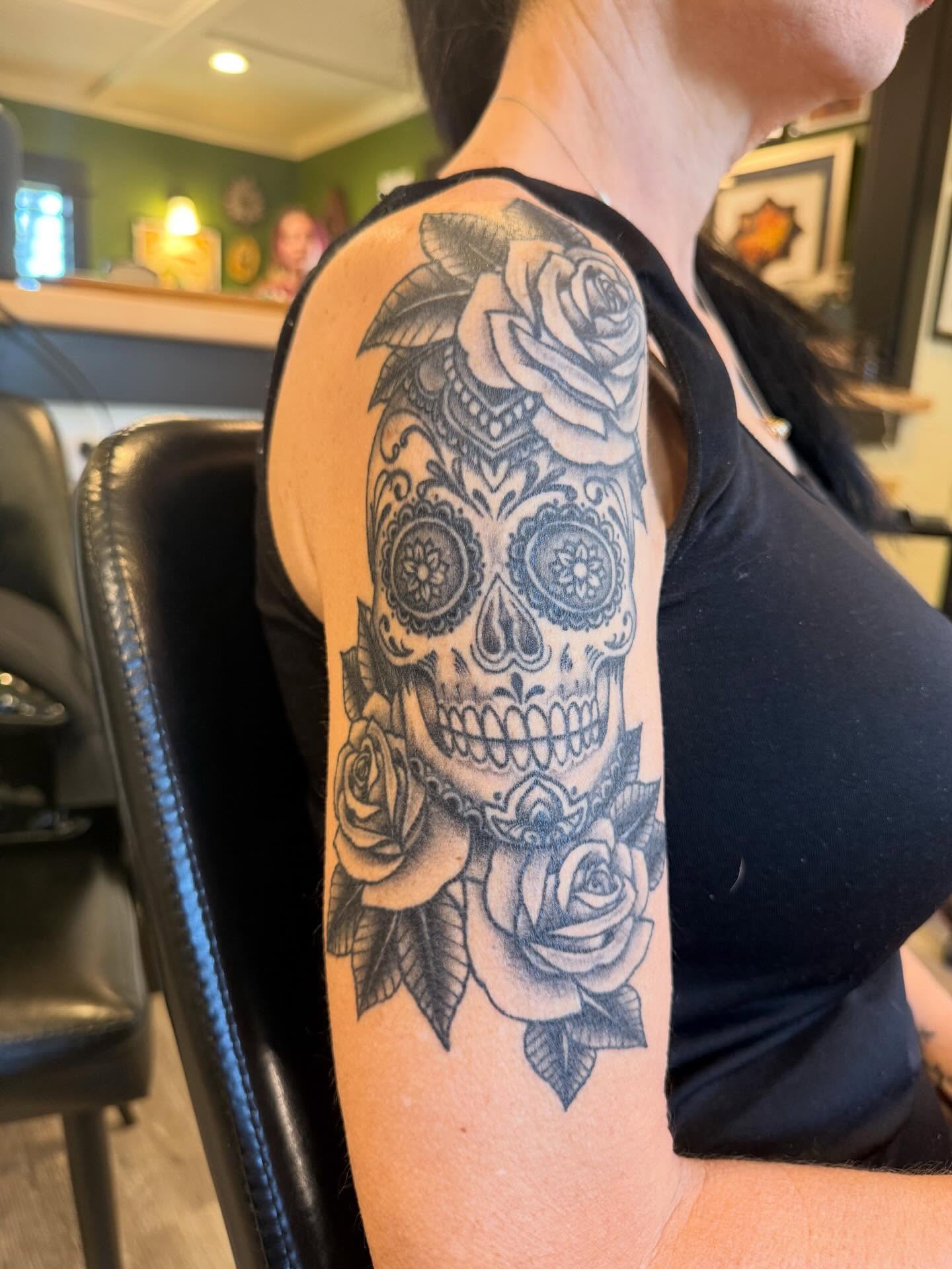 Sugar skull with roses black and grey tattoo on the upper arm by Rebecca Basma Smith
