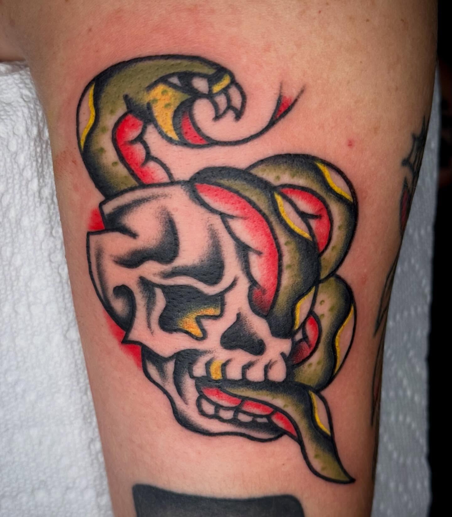 Skull with snake American traditional tattoo on the forearm by Ty Elias