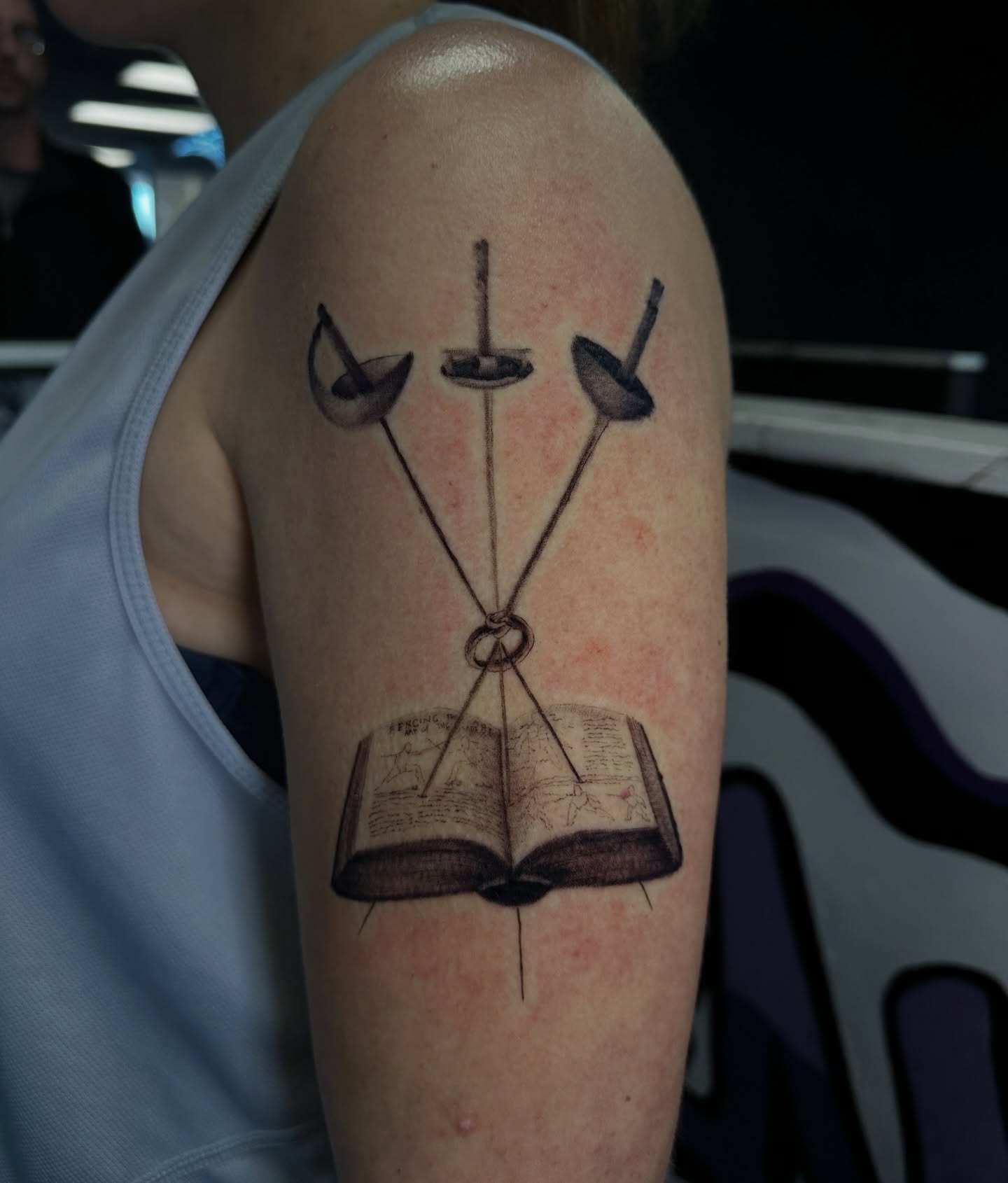 Open book with crossed swords black and grey tattoo on the forearm by Angel Tattoos