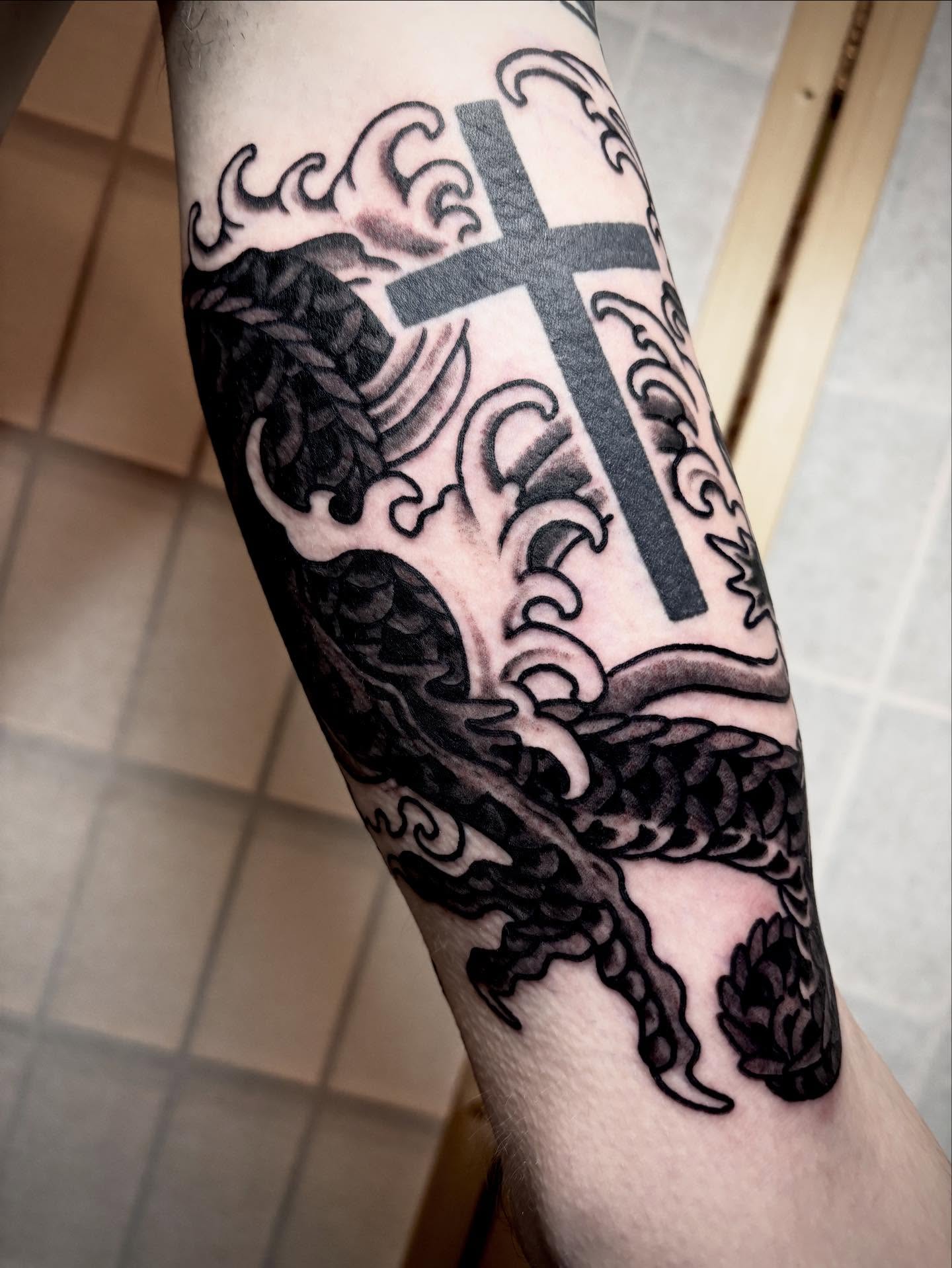 Cross and dragon black and grey tattoo on the forearm by ๐๐ซ๐ข๐ ๐๐ฅ๐ญ๐จ๐ง๐๐ง