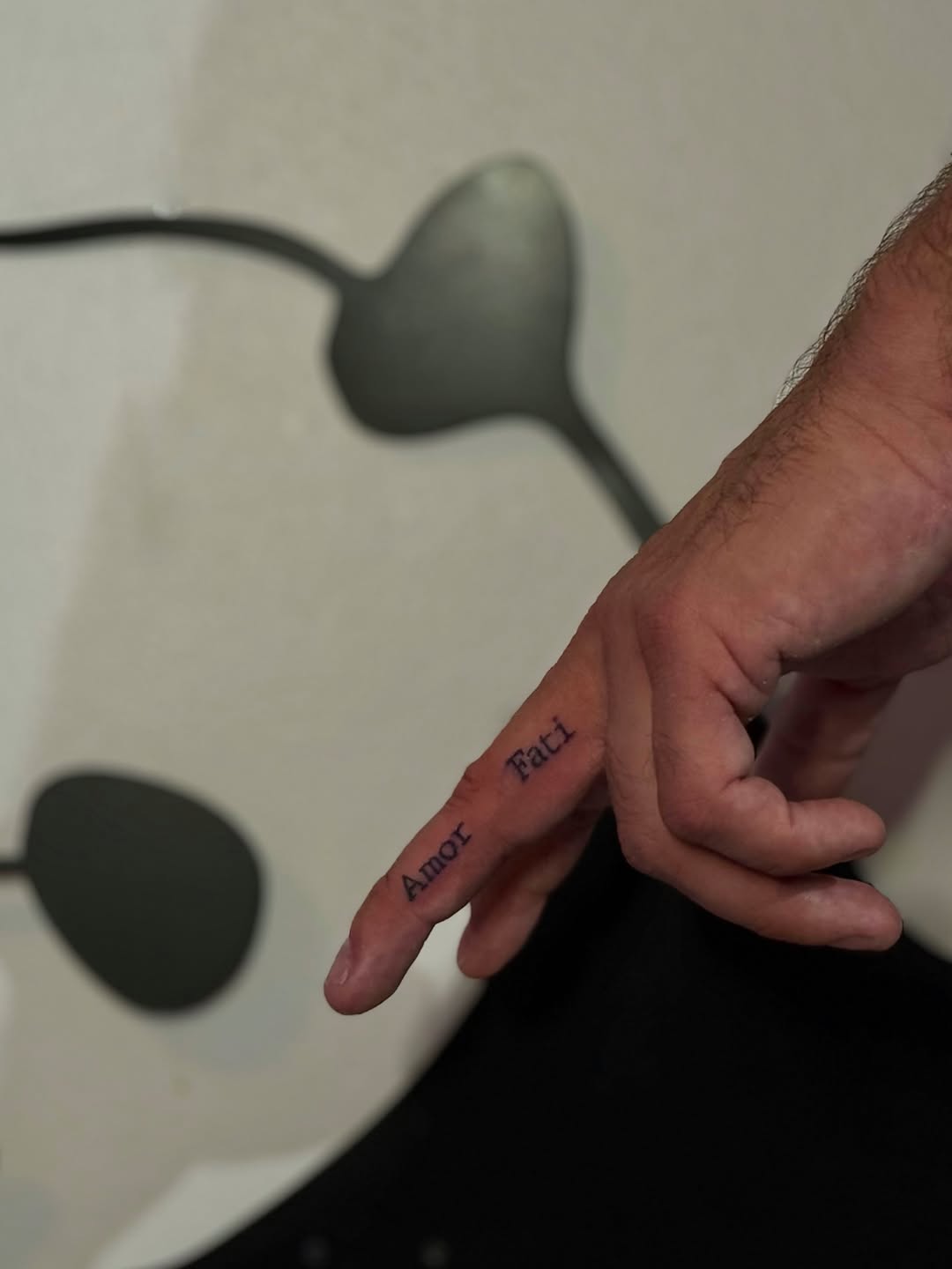 Amor Fati lettering lettering tattoo on the hand by @blackastaratattoo