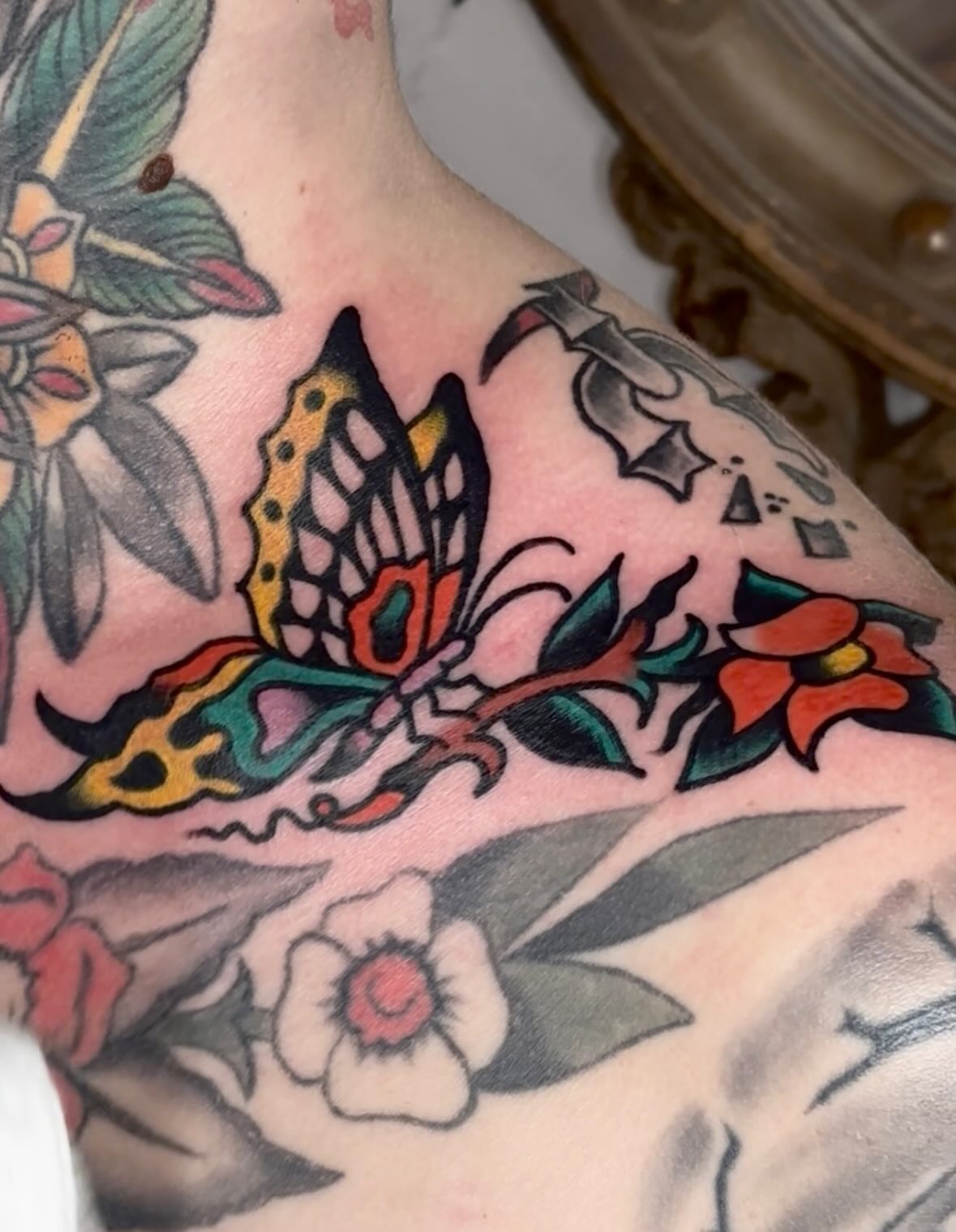 Butterfly and flowers American traditional tattoo on the chest by Steve Pearson