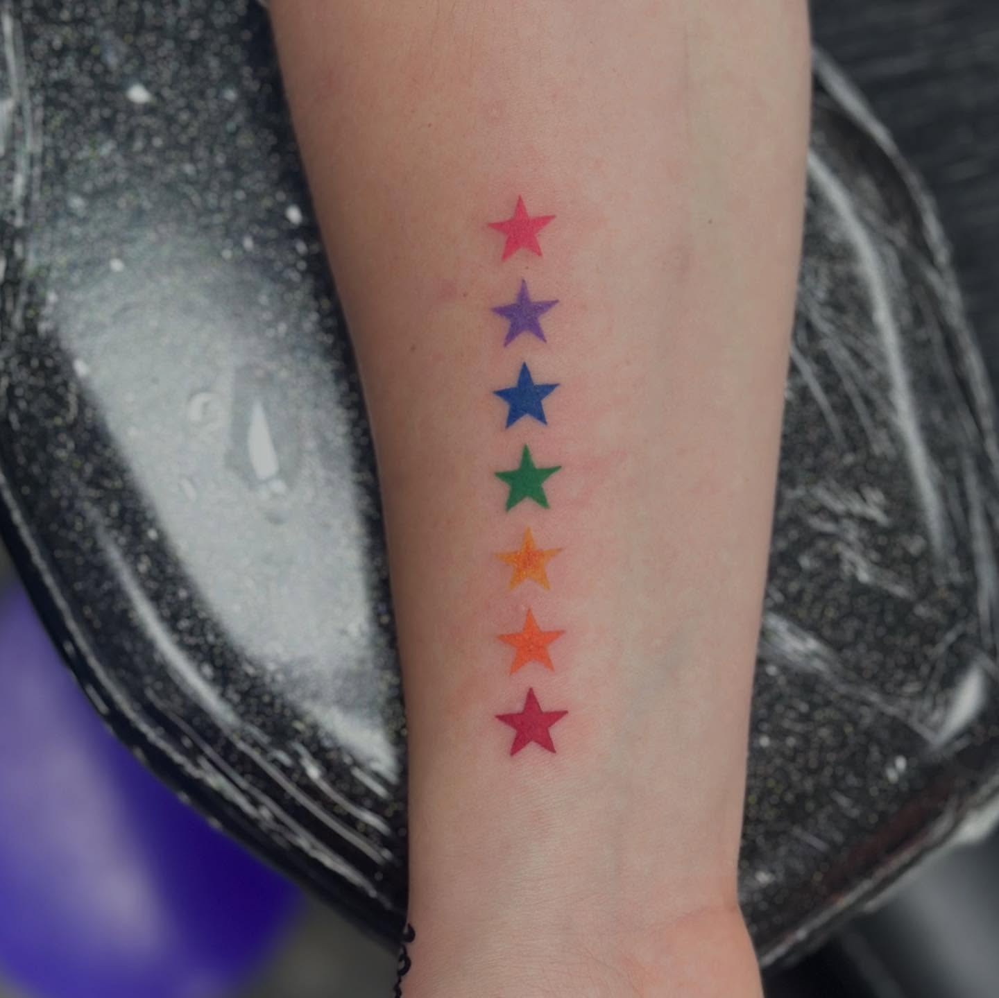 Rainbow stars dotwork tattoo on the forearm by Olivia Norbert