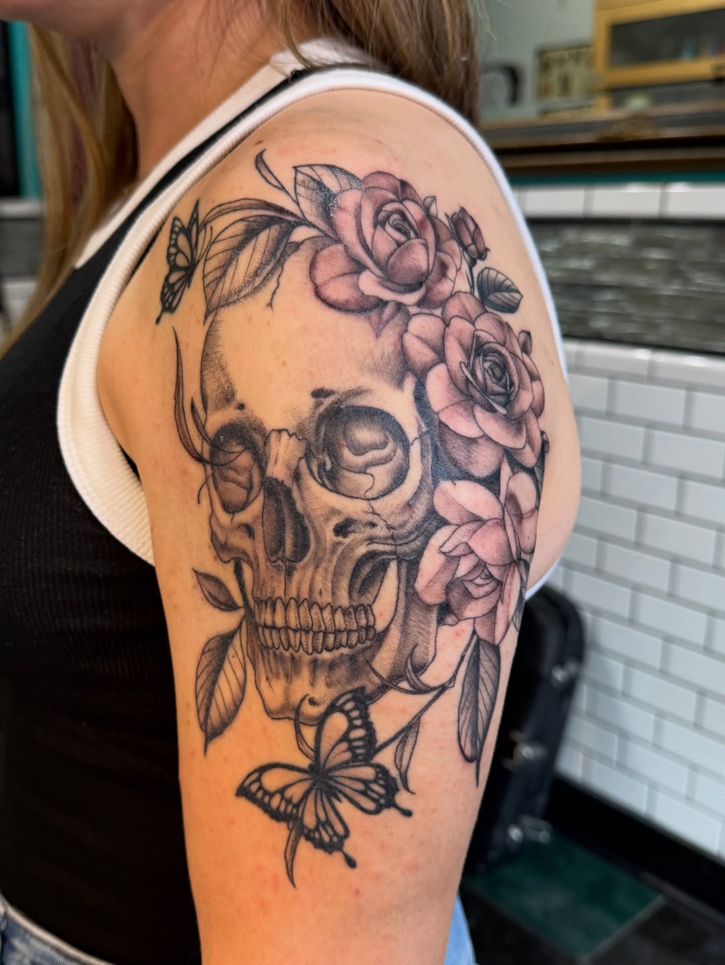Skull with roses realism tattoo on the shoulder by Devin Derbes