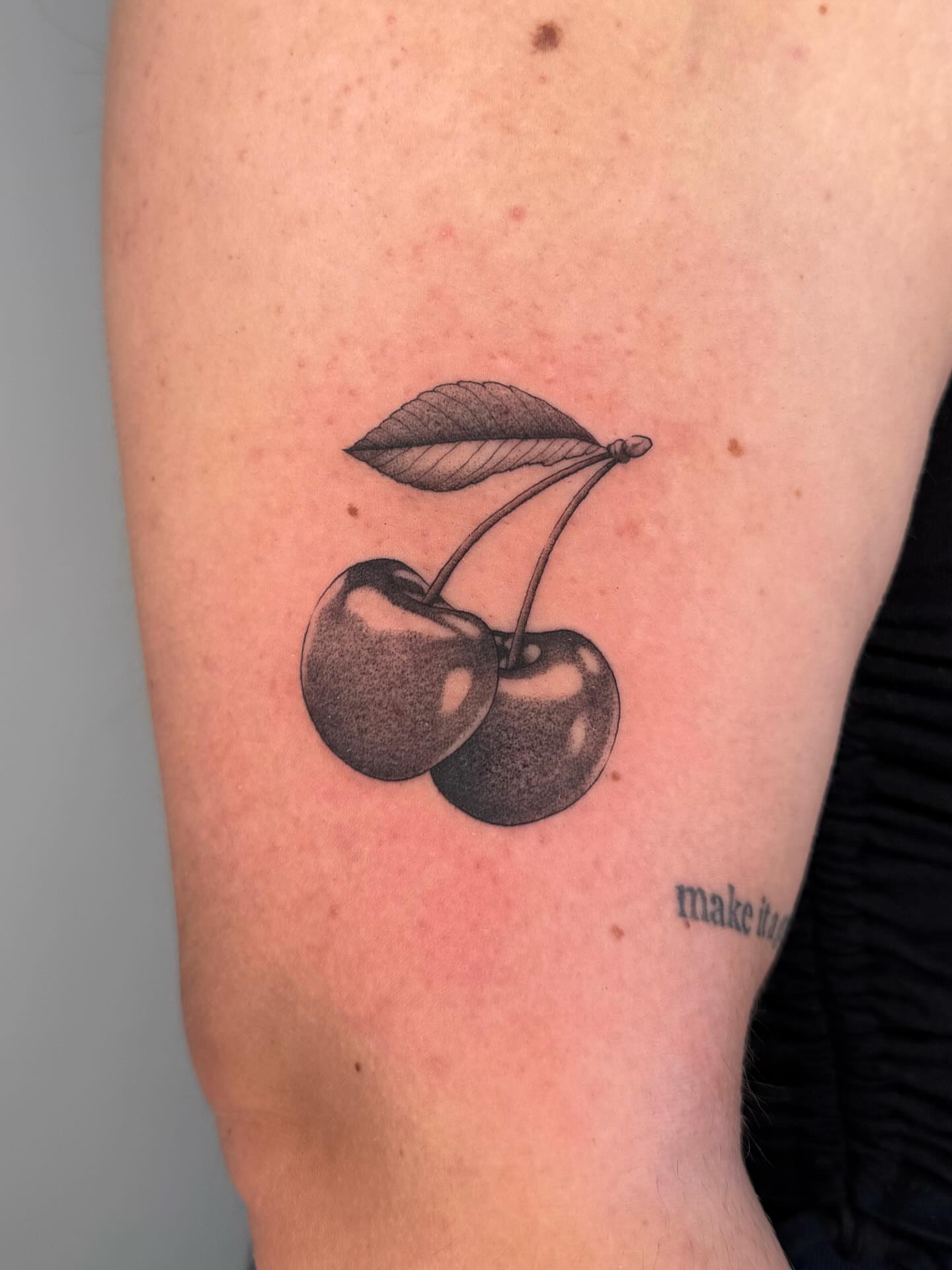 Cherries black and grey tattoo on the forearm by Maddie Hammell