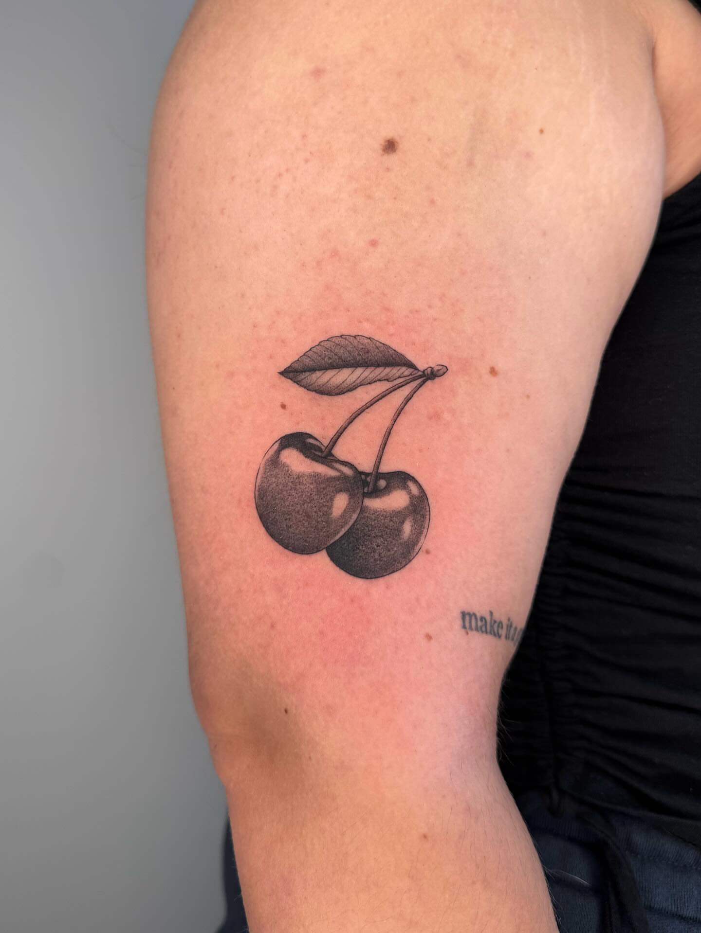 Cherries black and grey tattoo on the forearm by Maddie Hammell
