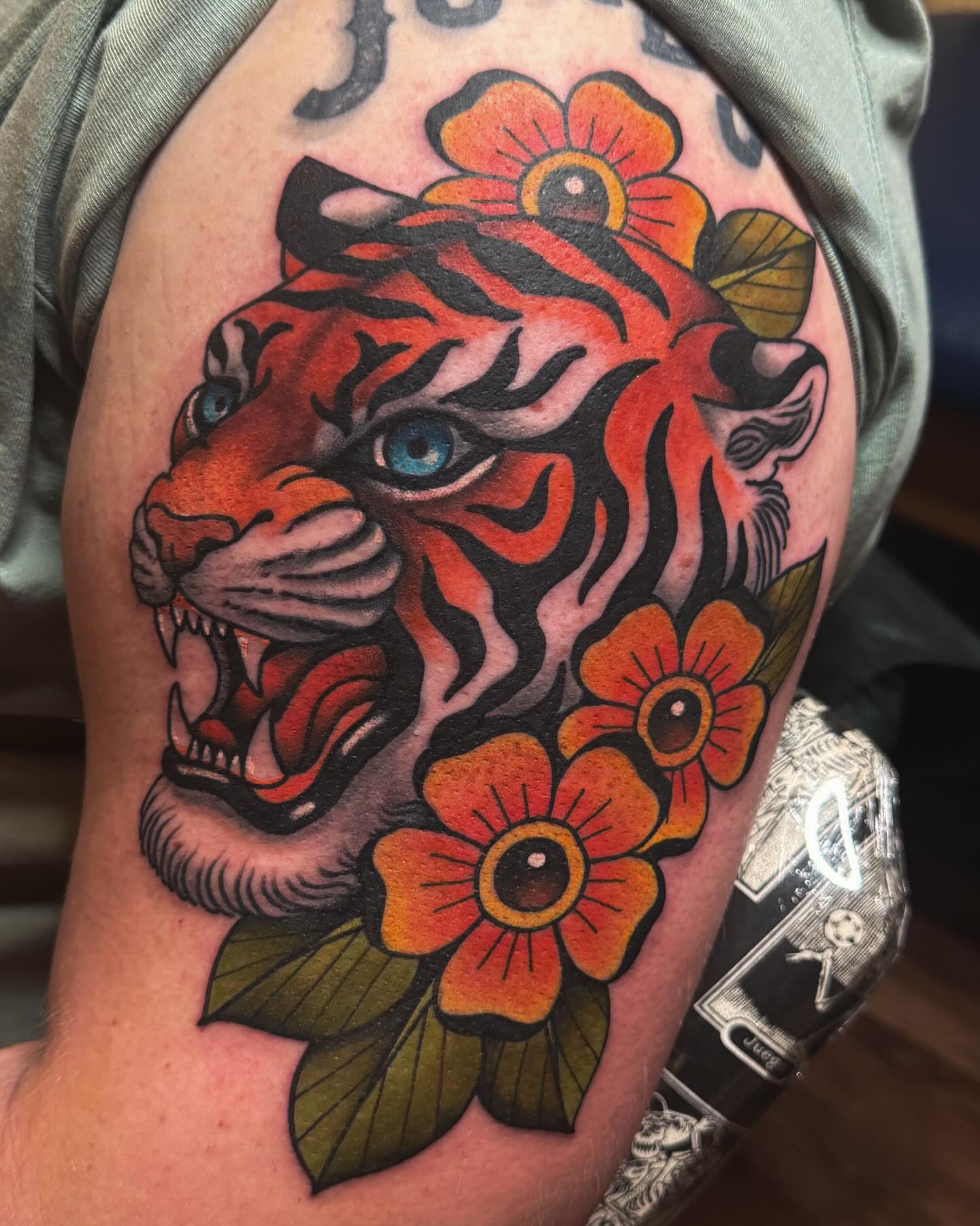 Tiger head with flowers American traditional tattoo on the shoulder by Monica Amneus
