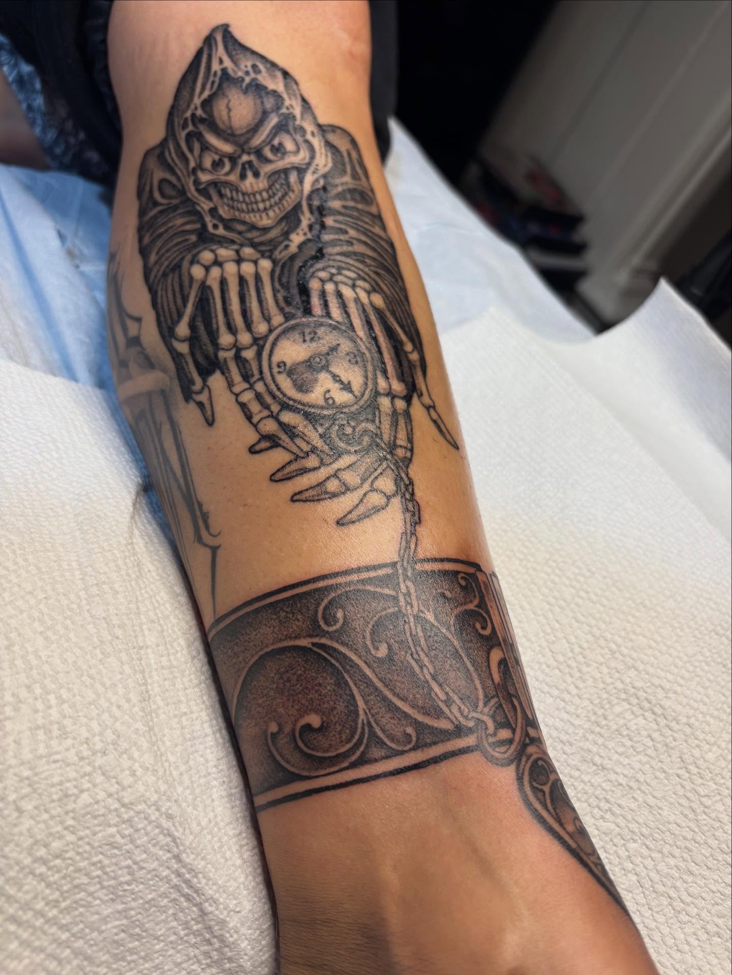 Skeleton holding clock realism tattoo on the forearm by Brendan Smith