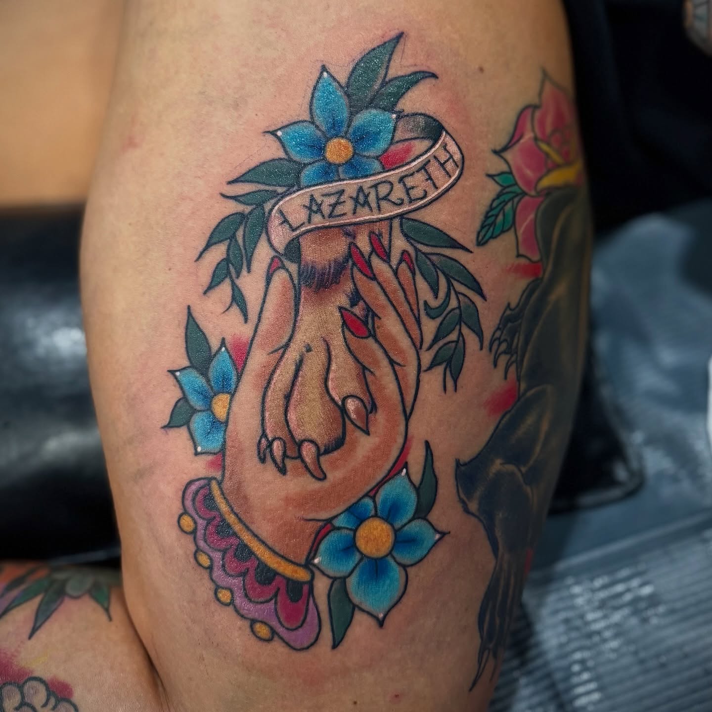 Hand with flowers American traditional tattoo on the thigh by David C. McGhee