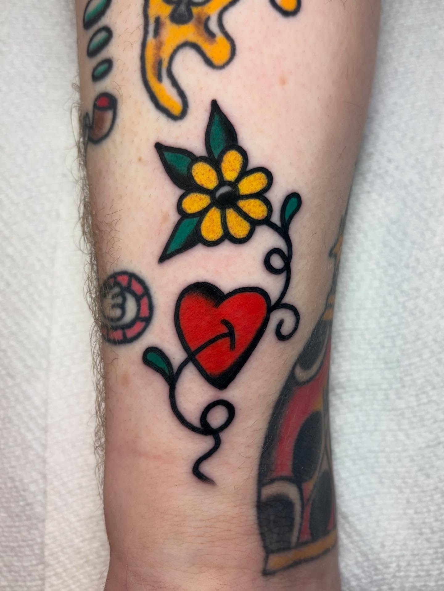 Heart and flower American traditional tattoo on the forearm by Traditional Tattooing