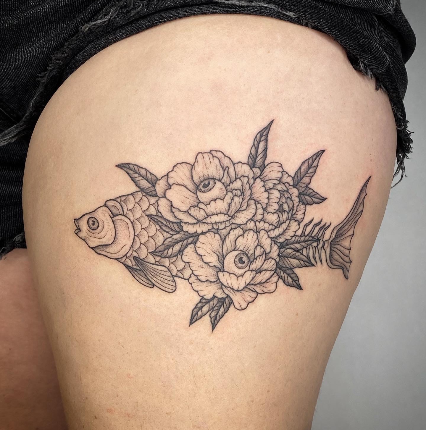 Fish and flowers black and grey tattoo on the thigh by Carmen Figueroa, New York, New York