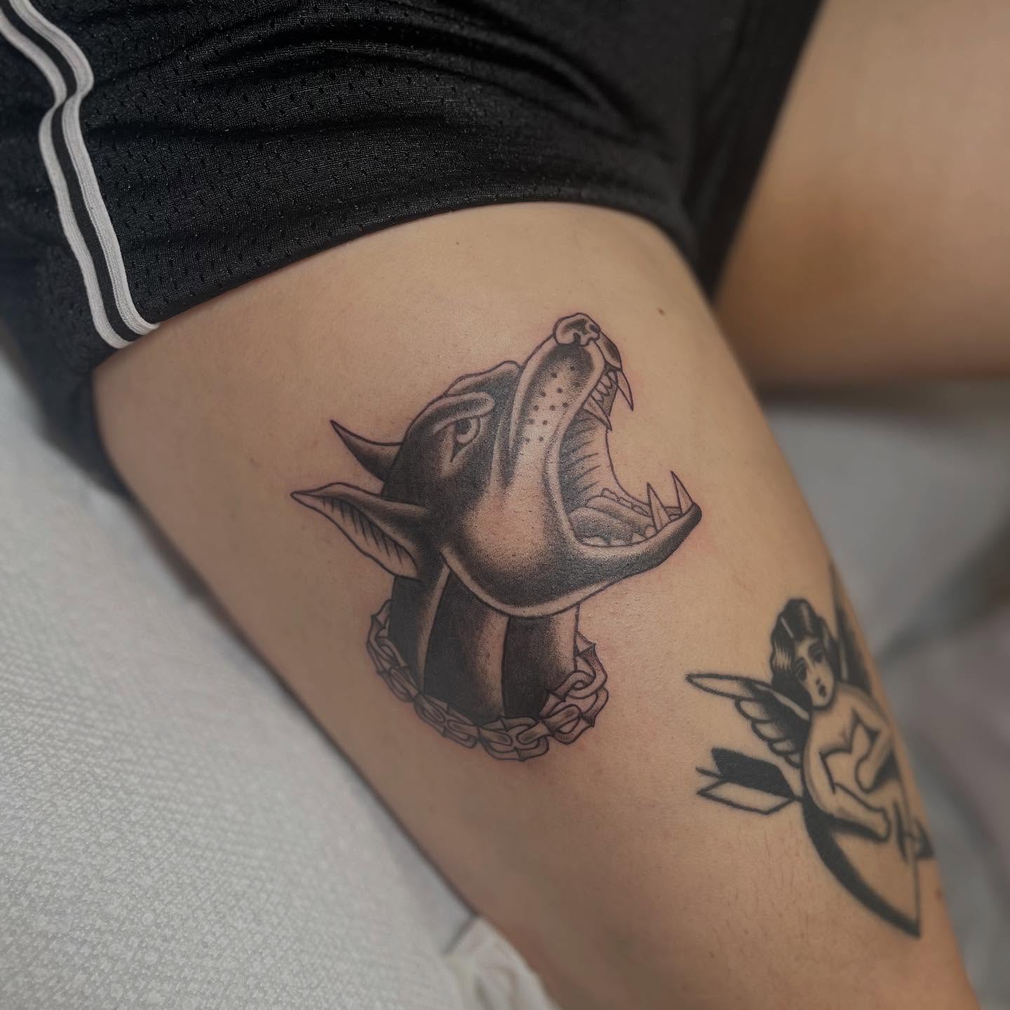 Roaring dog black and grey tattoo on the thigh by Maddy Anthony