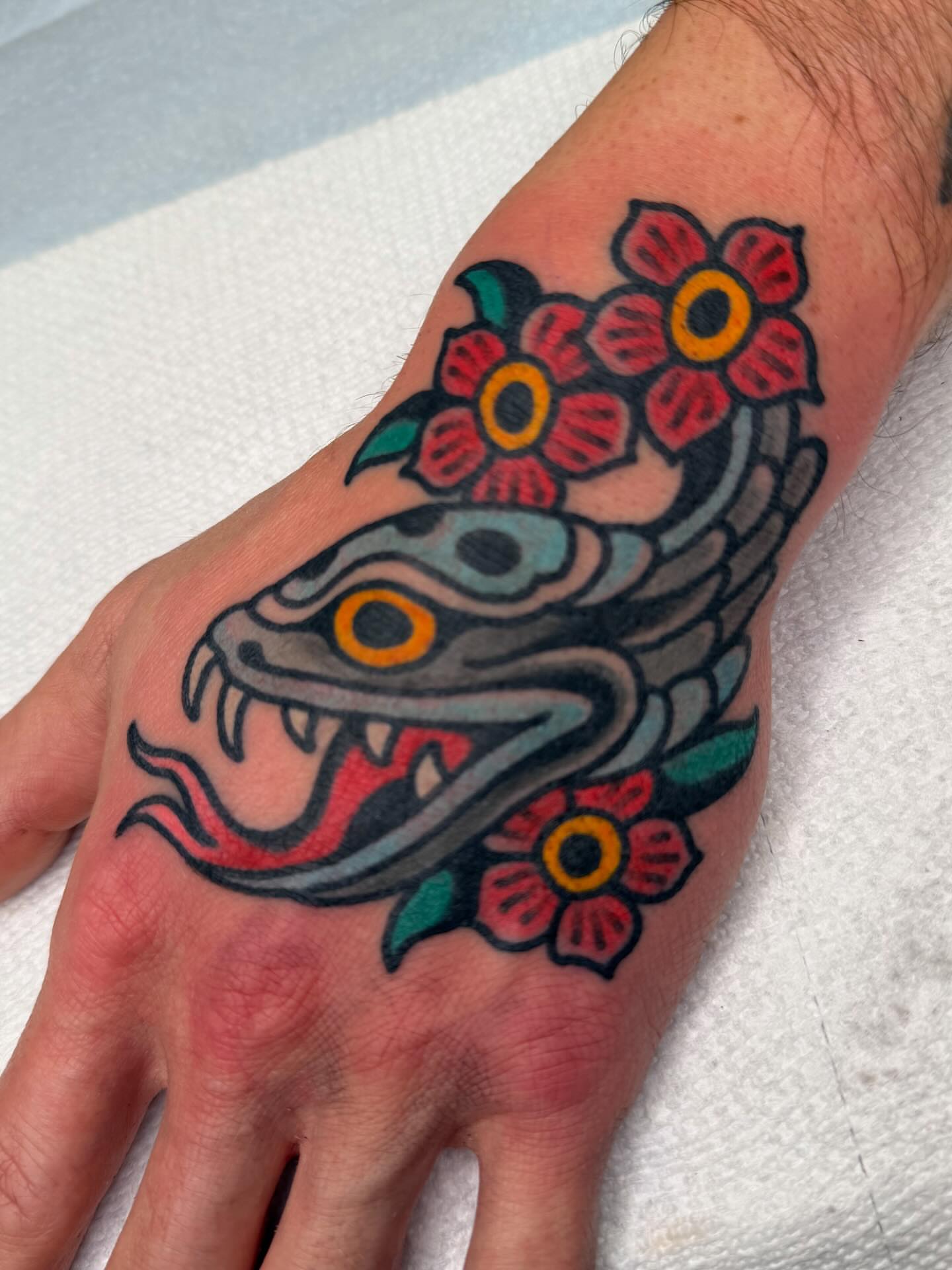 Snake and flowers American traditional tattoo on the hand by Danny Reed, Asheville, North Carolina