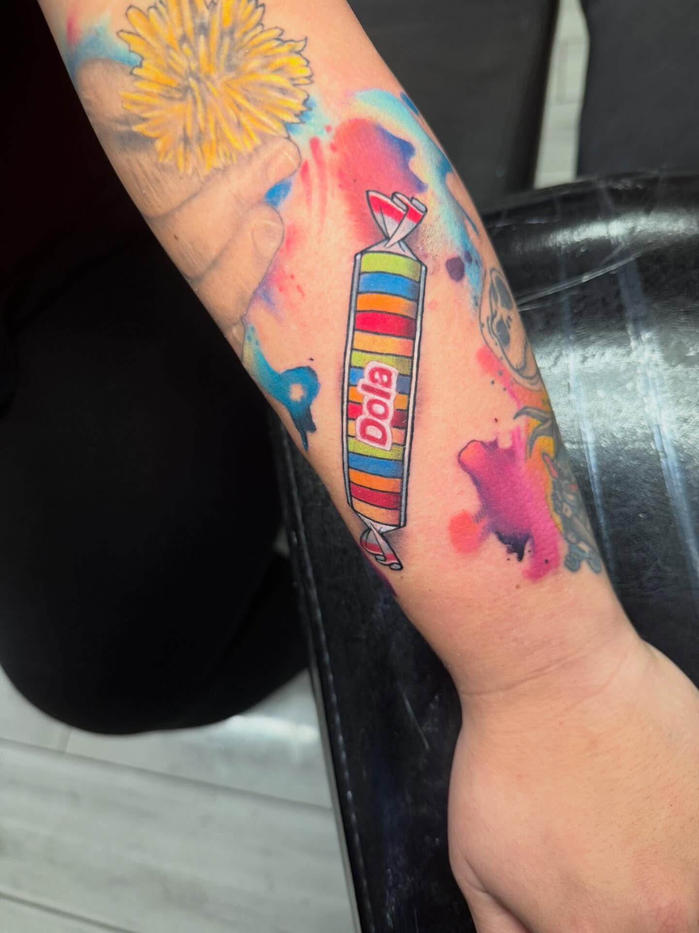 Candy bar watercolor tattoo on the forearm by Kenneth Ruiz