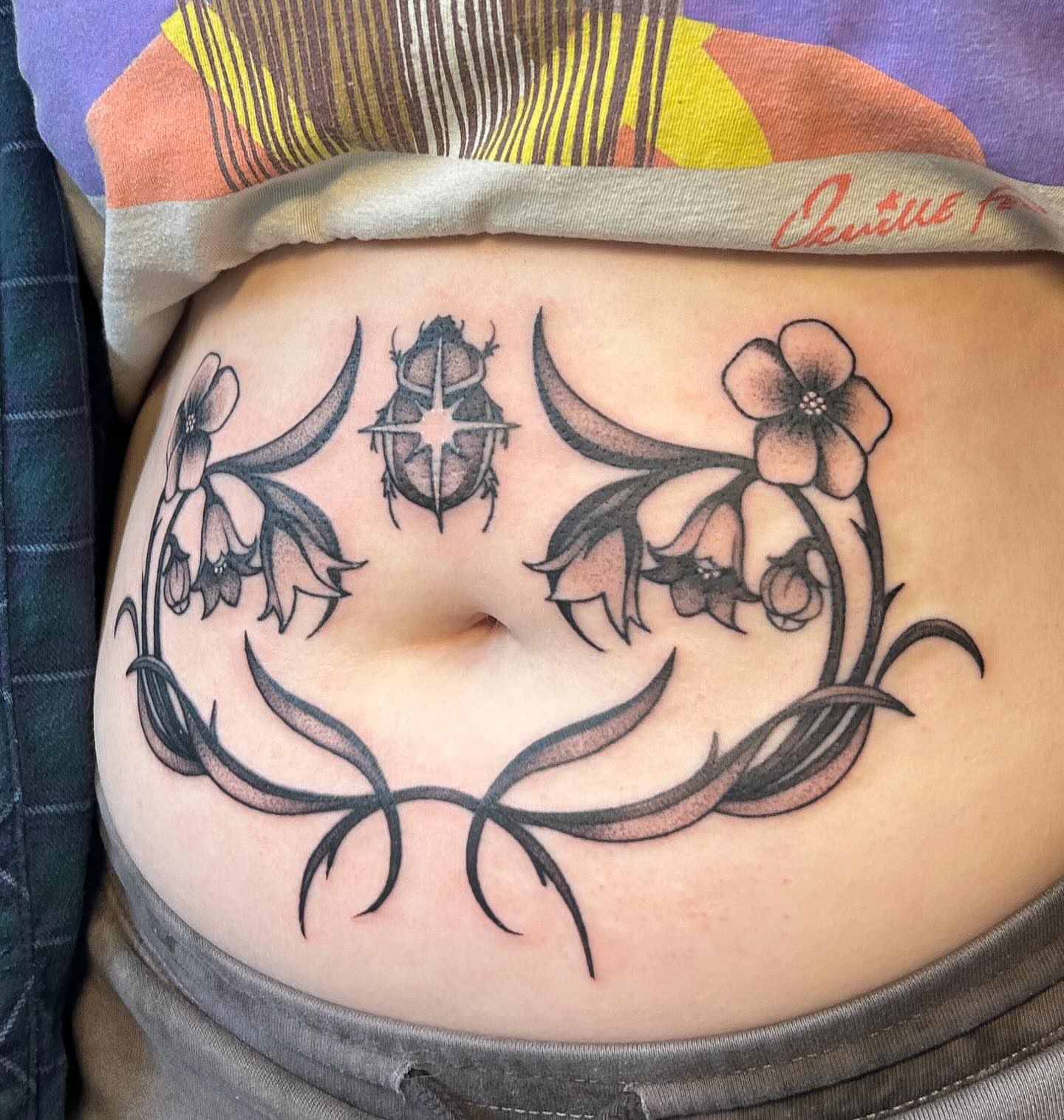 Bellflower and beetle dotwork tattoo on the torso by kuna ink