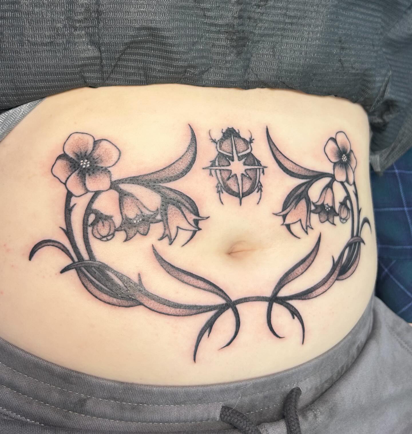 Flowers and beetle black and grey tattoo on the torso by kuna ink