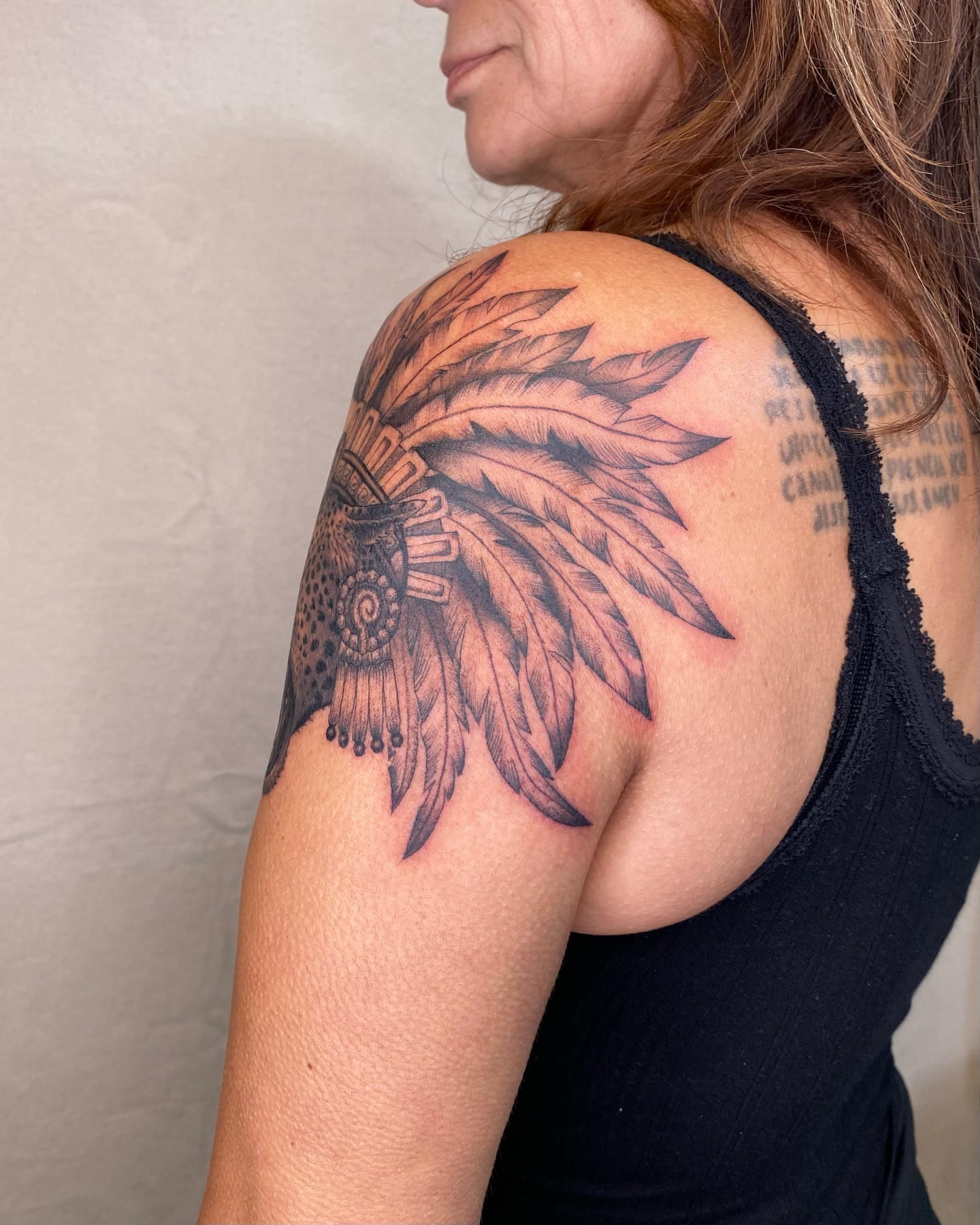 Feather headdress black and grey tattoo on the shoulder by Sasha 🪆 Southern California Tattoo Artist