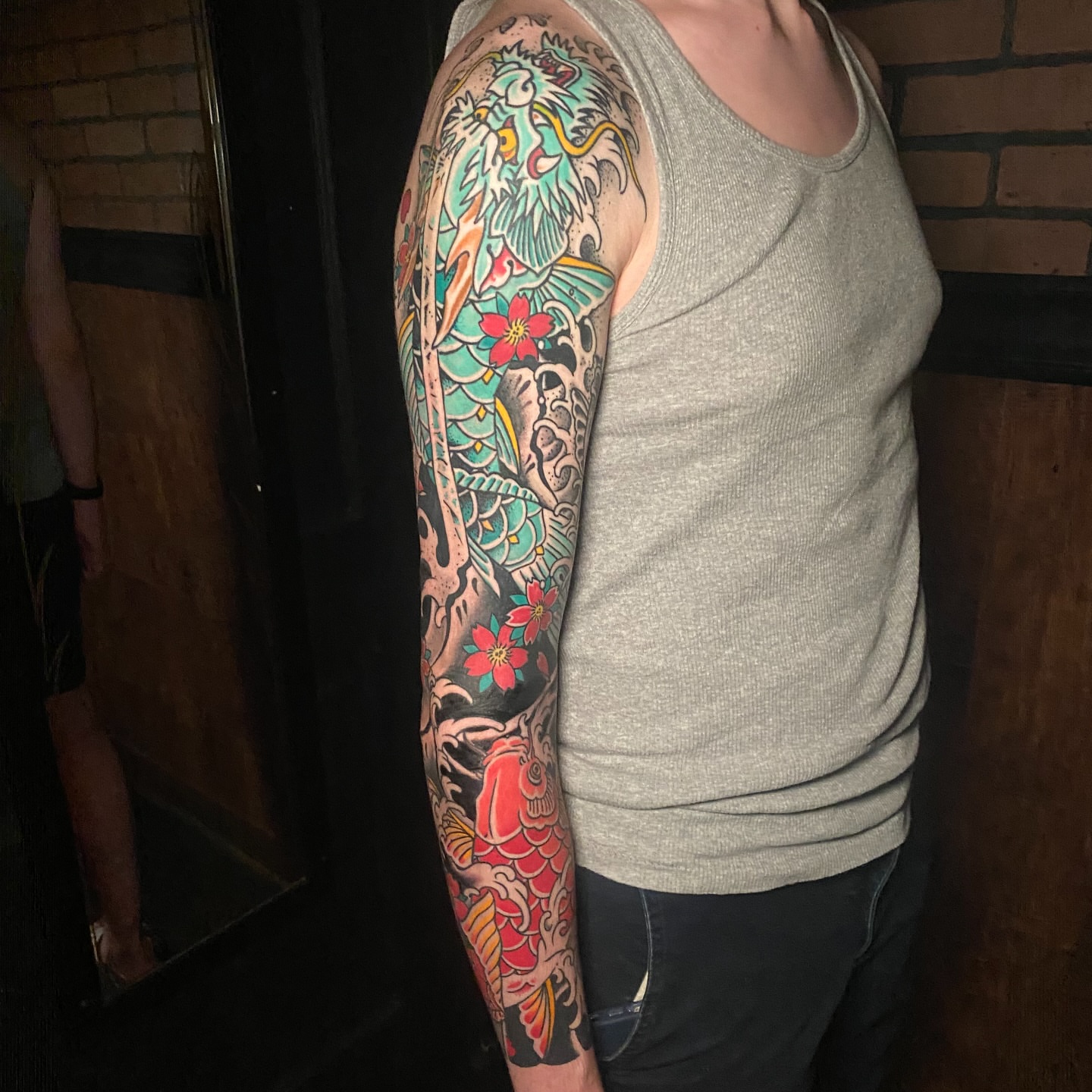 Koi fish and dragon American traditional tattoo on the upper arm by Nick Weaver
