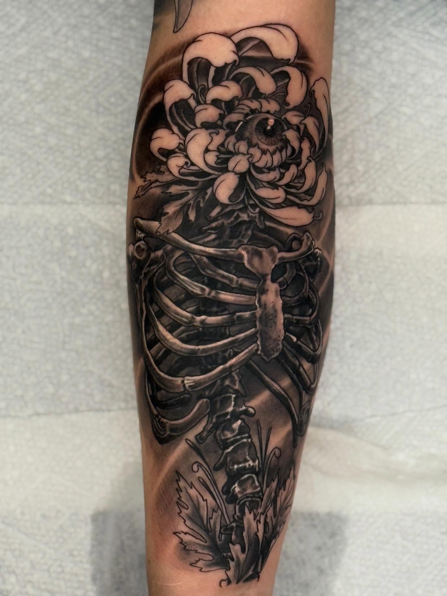 Human skeleton with chrysanthemum realism tattoo on the forearm by Frank DeMao