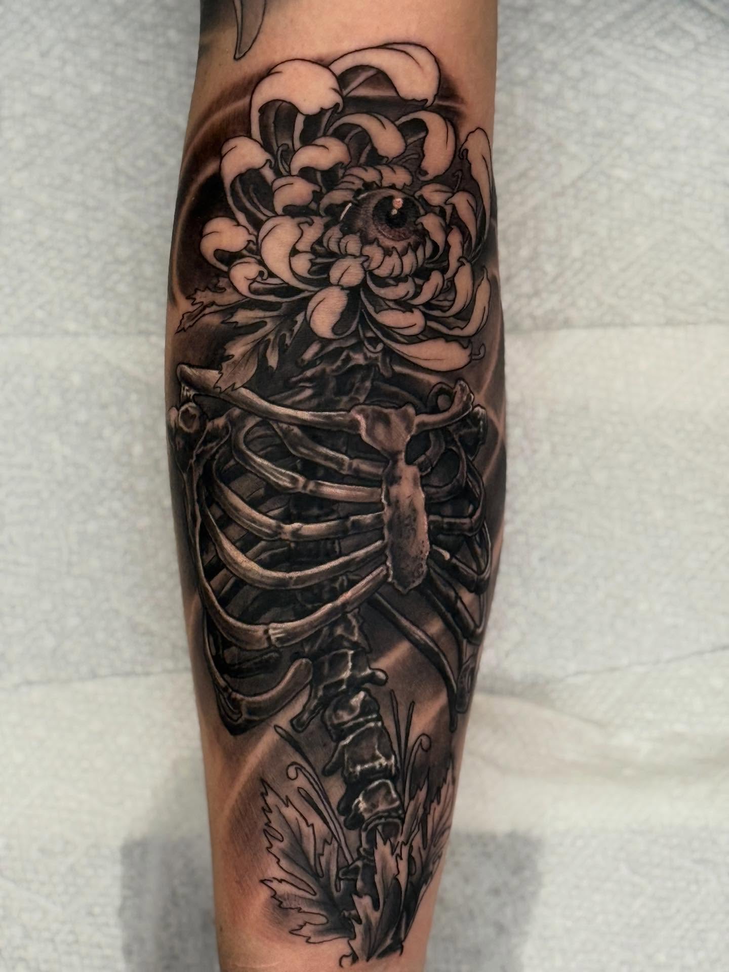 Chrysanthemum and skeleton realism tattoo on the forearm by Frank DeMao