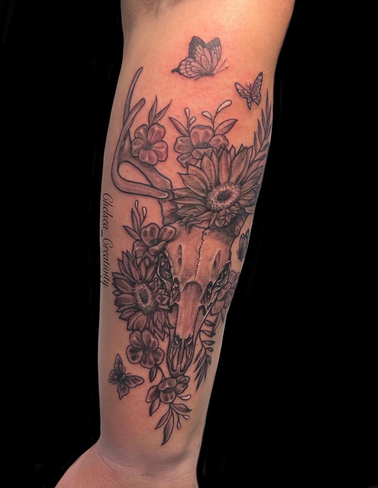 Deer skull with flowers realism tattoo on the forearm by Chelsea Nichole