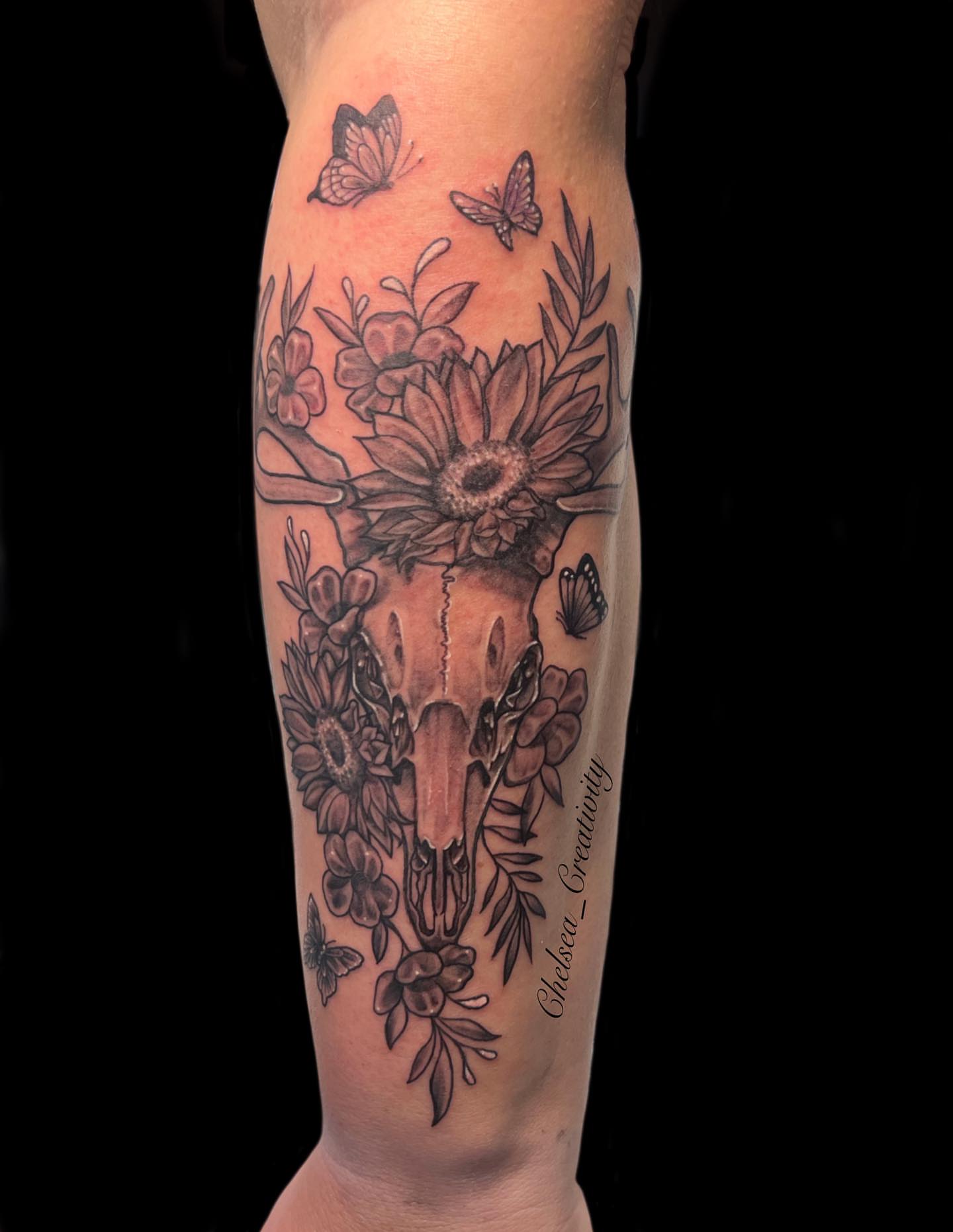 Deer skull with flowers realism tattoo on the forearm by Chelsea Nichole