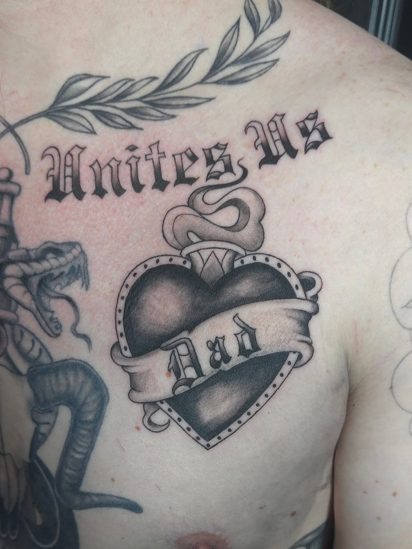 Heart with banner American traditional tattoo on the chest by Trinity