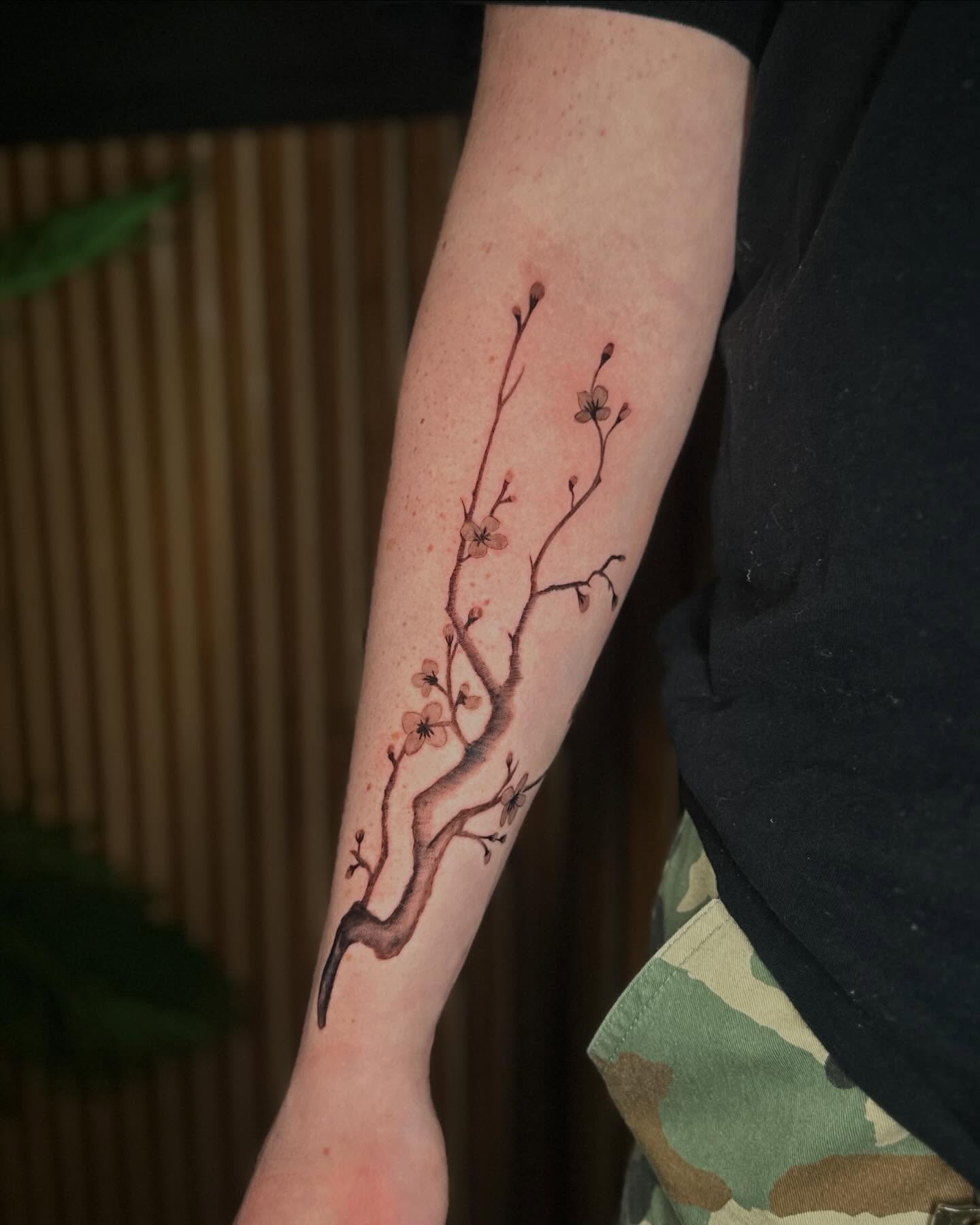Cherry blossom branch watercolor tattoo on the forearm by Felipe Pacifico
