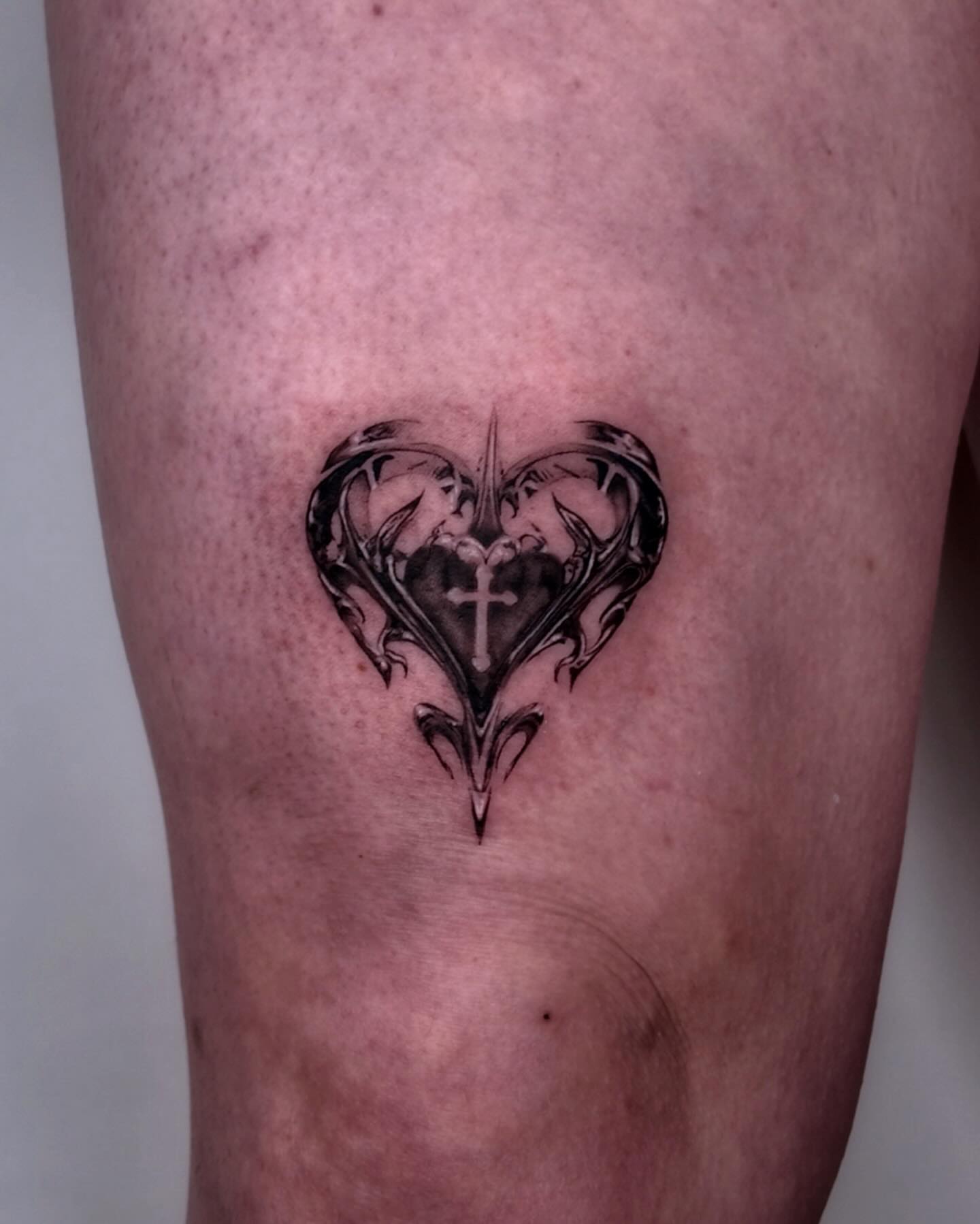 Heart with cross black and grey tattoo on the leg by Gabriel