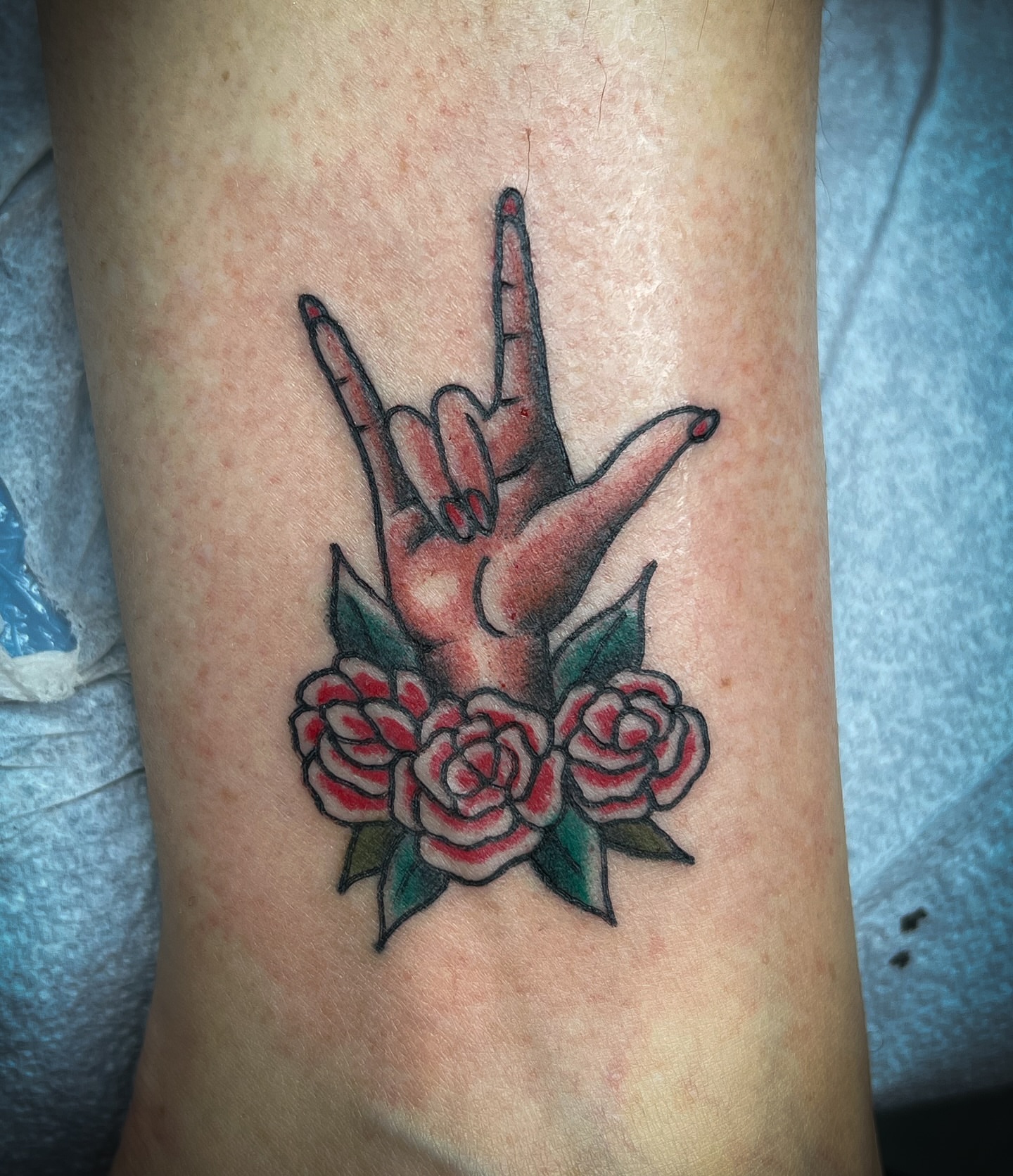 Rock sign with roses American traditional tattoo on the forearm by Scott Allen