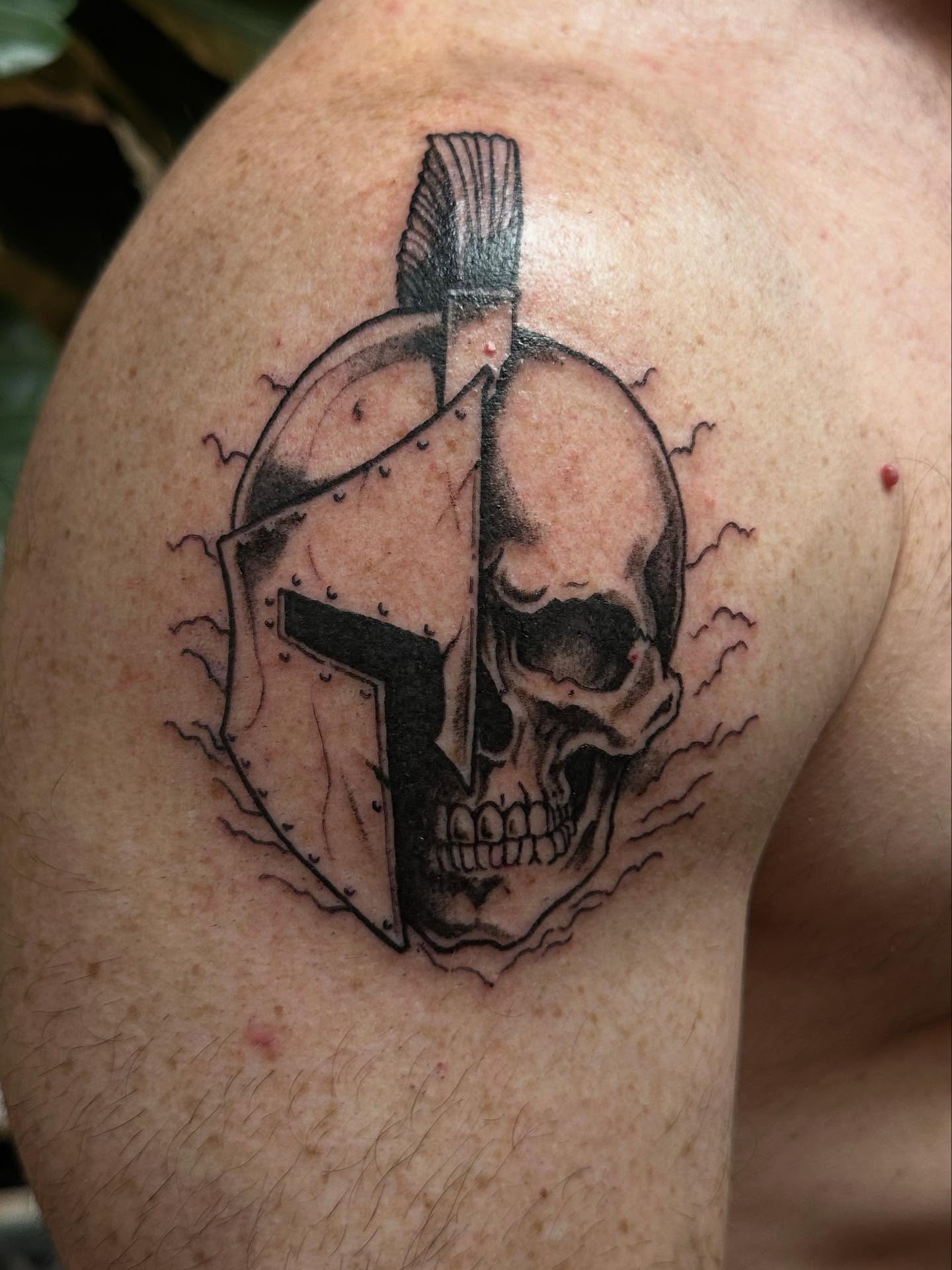 Skull and helmet black and grey tattoo on the shoulder by Ben Cisek