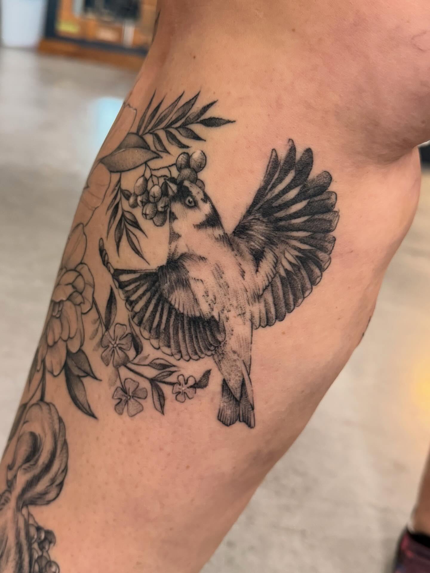 Bird with floral elements realism tattoo on the forearm by Susie Maj