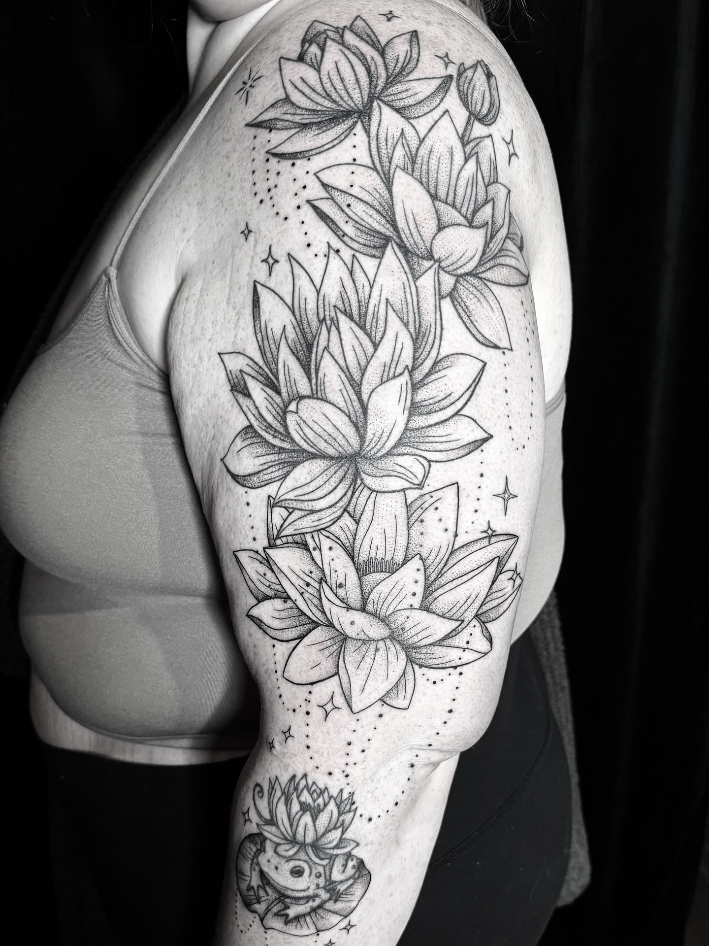 Lotus flowers dotwork tattoo on the upper arm by Breezy Tucker