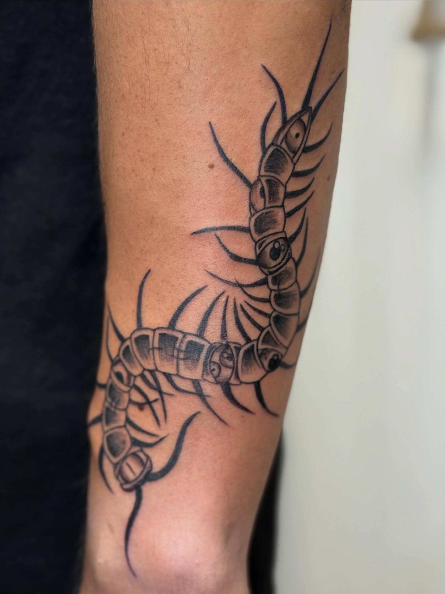 Centipede black and grey tattoo on the forearm by Rigo Vargas