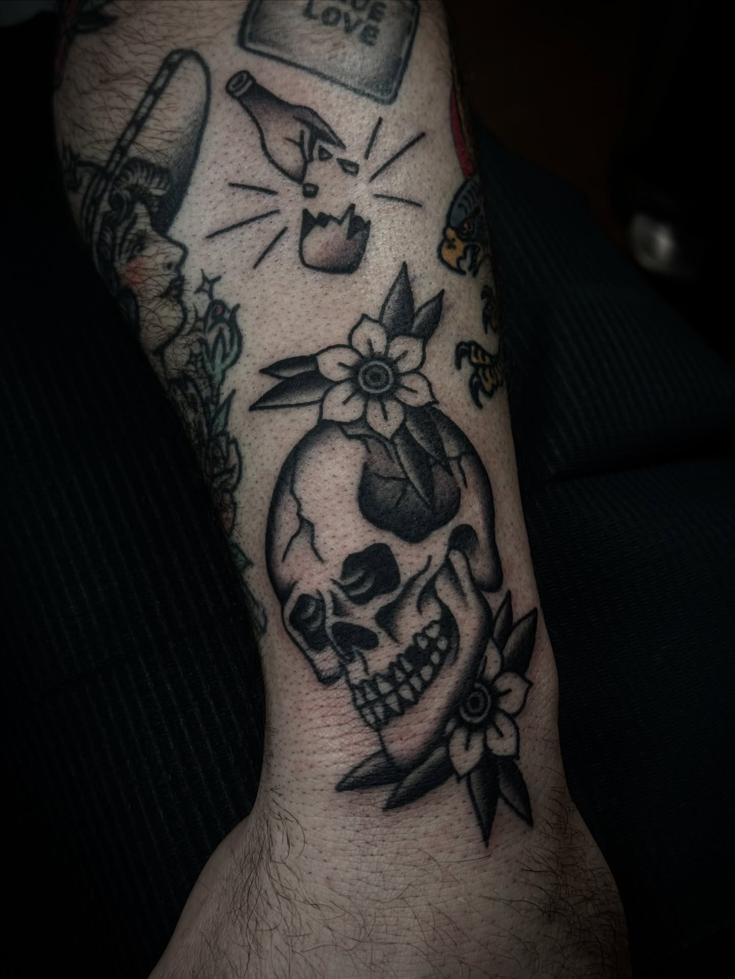 Skull with flowers black and grey tattoo on the forearm by Ally noel