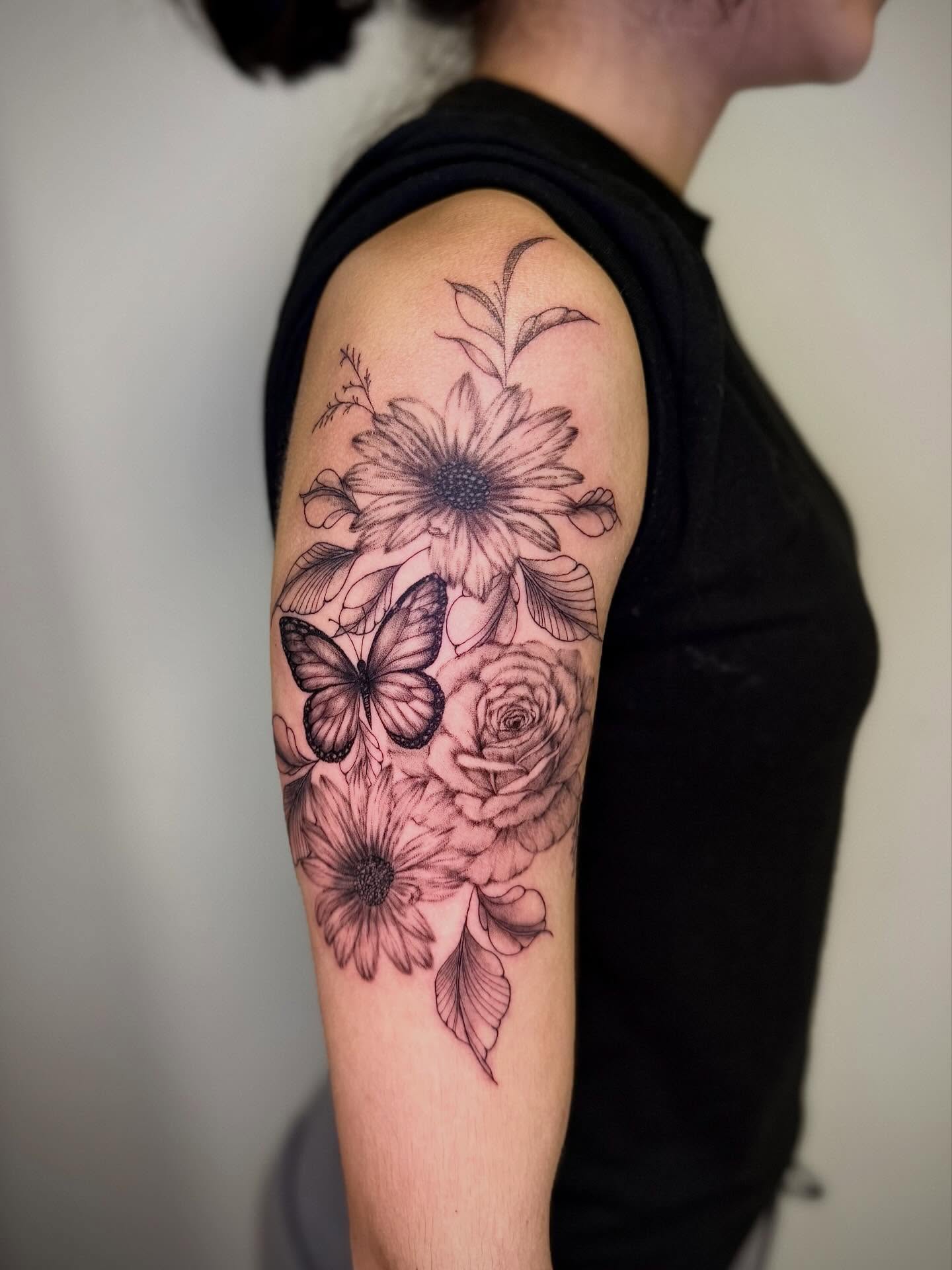 Flowers and butterfly black and grey tattoo on the upper arm by Cat girl tattoo