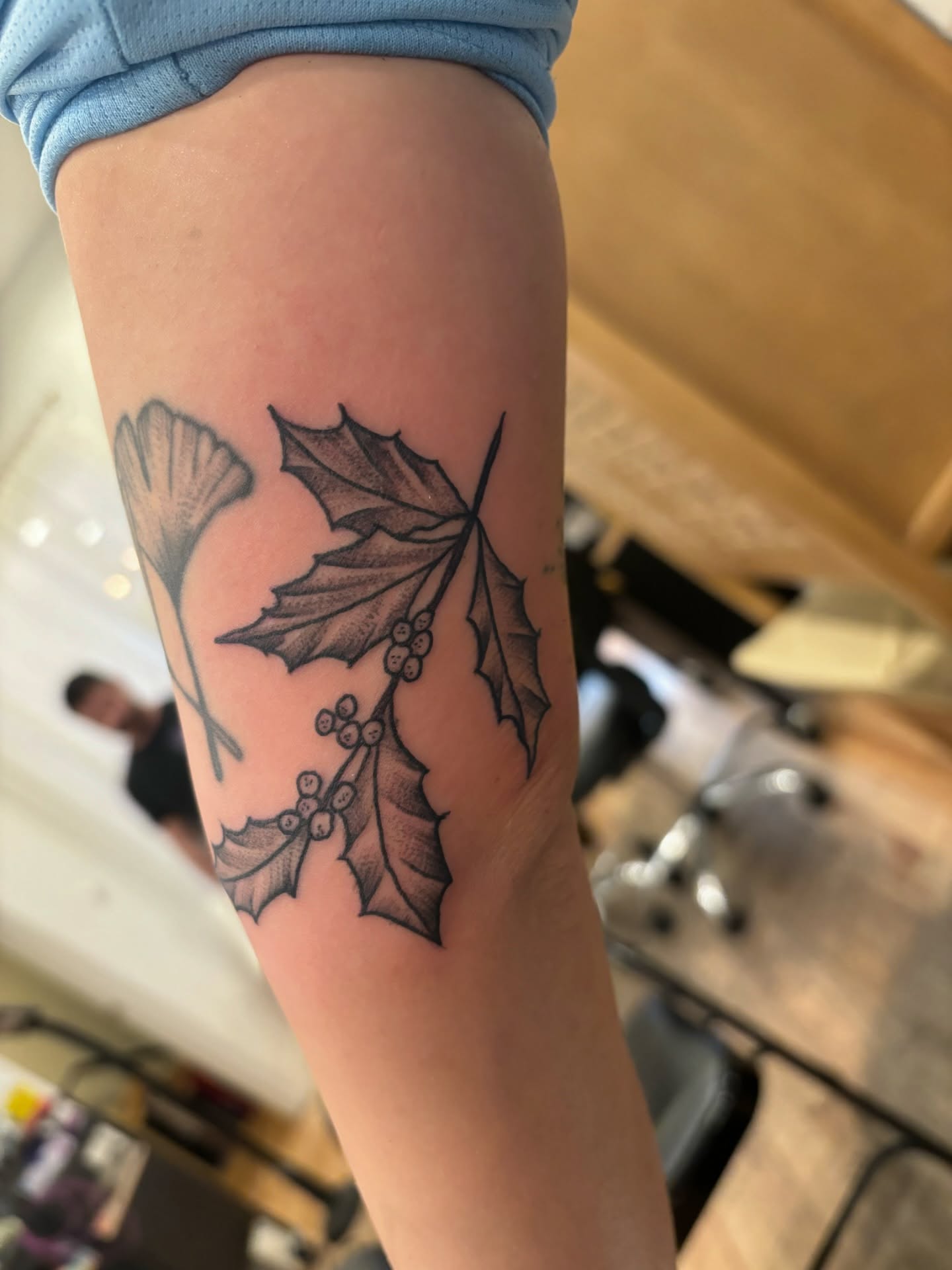 Holly leaves and berries black and grey tattoo on the forearm by Francis Cassidy