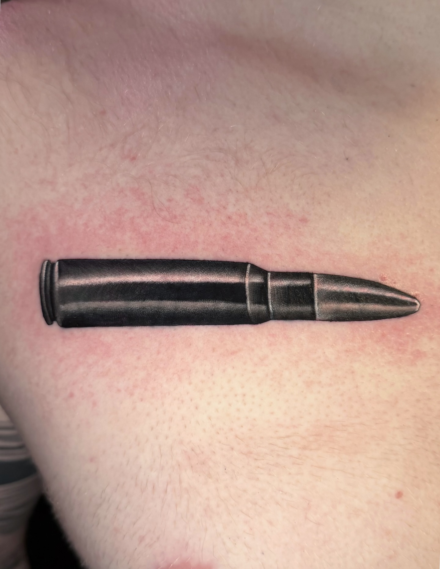 Bullet black and grey tattoo on the chest by Savannah Compton