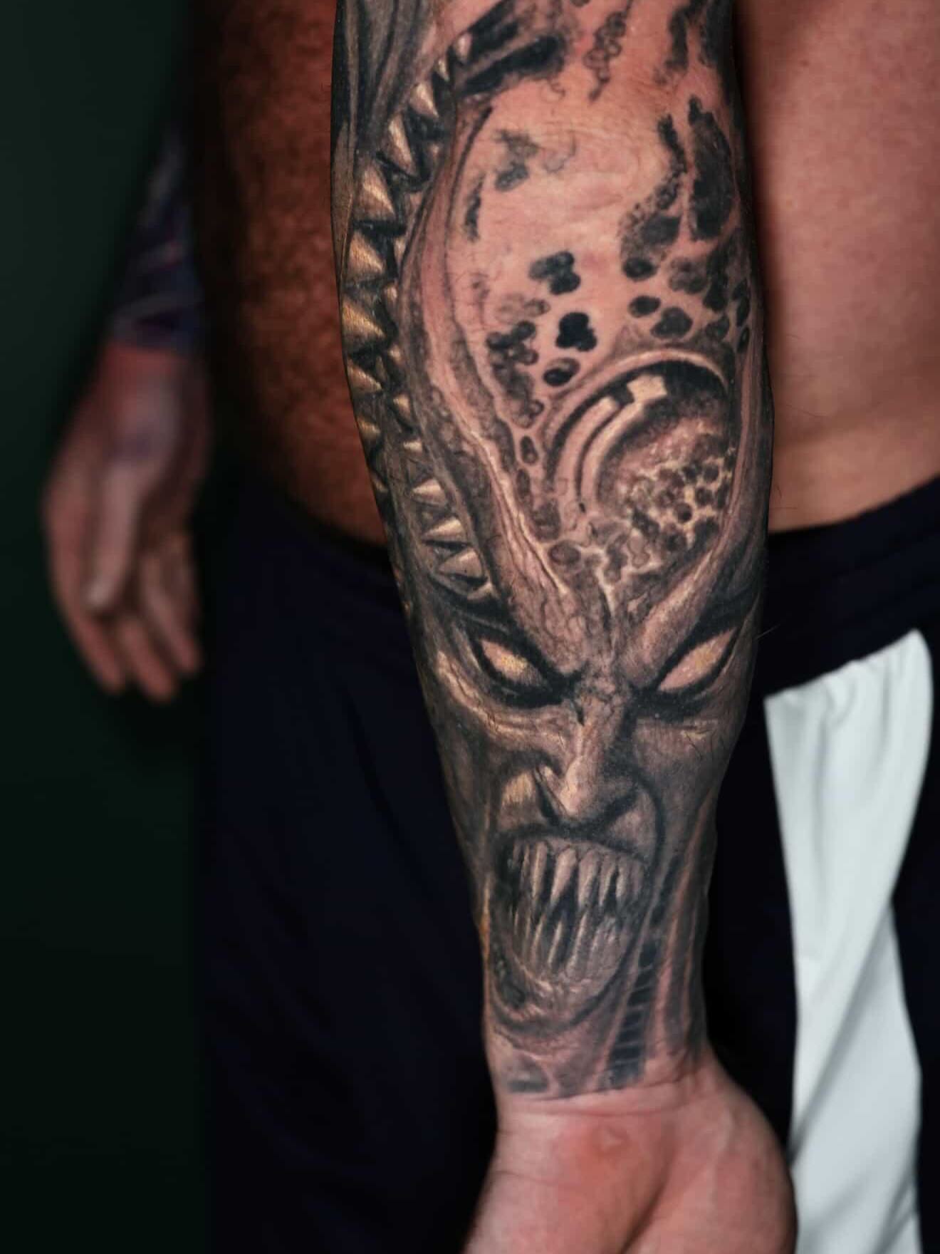 Alien head realism tattoo on the forearm by Paul Booth