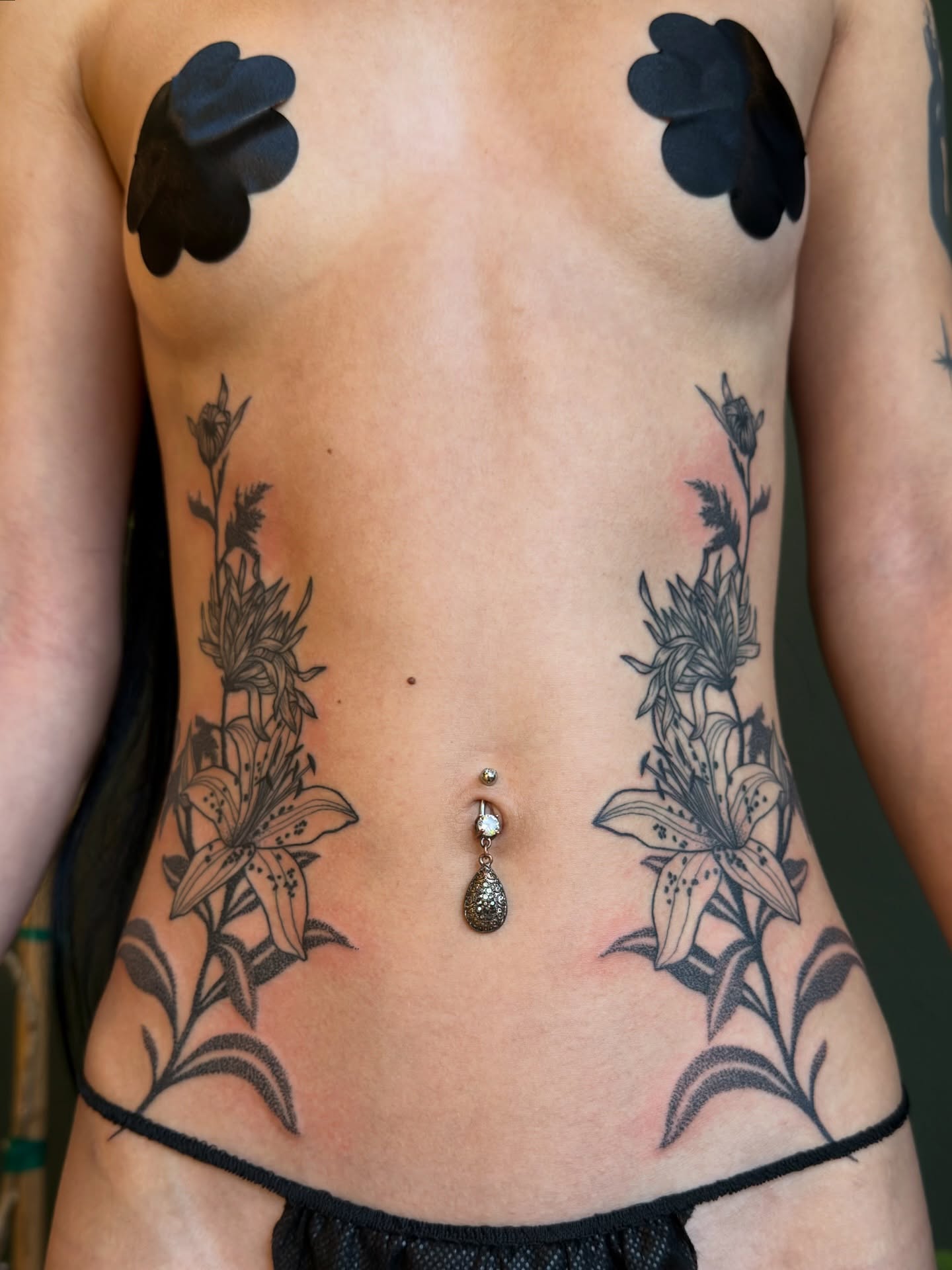 Lilies black and grey tattoo on the torso by Alexandra Gray
