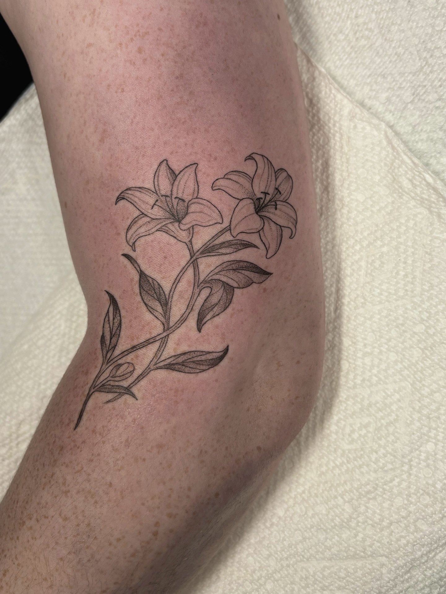 Lilies black and grey tattoo on the forearm by Fineline tattoos by Kinsey