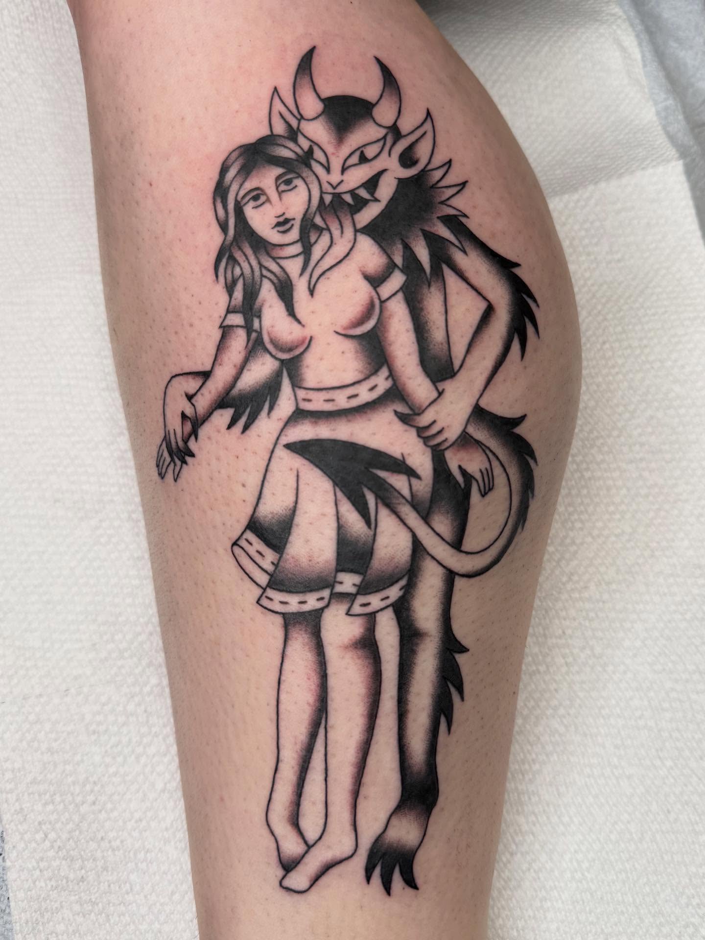 Demon and woman black and grey tattoo on the thigh by Emma Eaton
