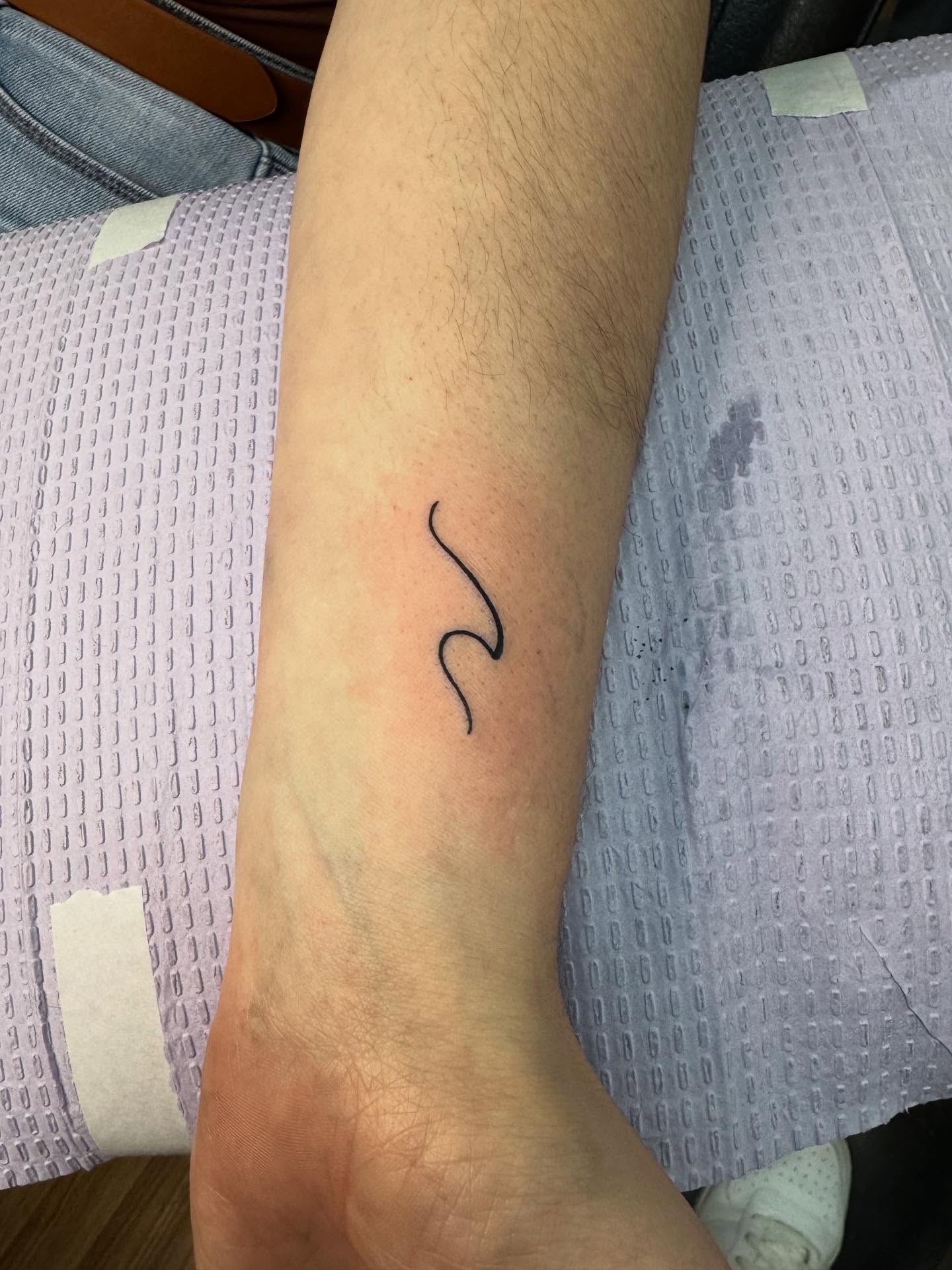 Wave minimalist tattoo on the forearm by Justin Fiveson