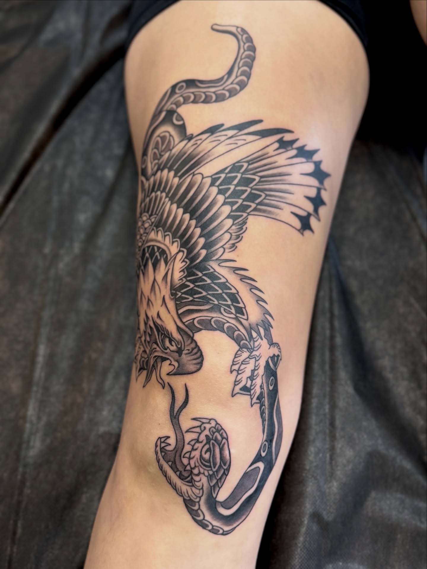 Phoenix black and grey tattoo on the thigh by Ernie Rivera