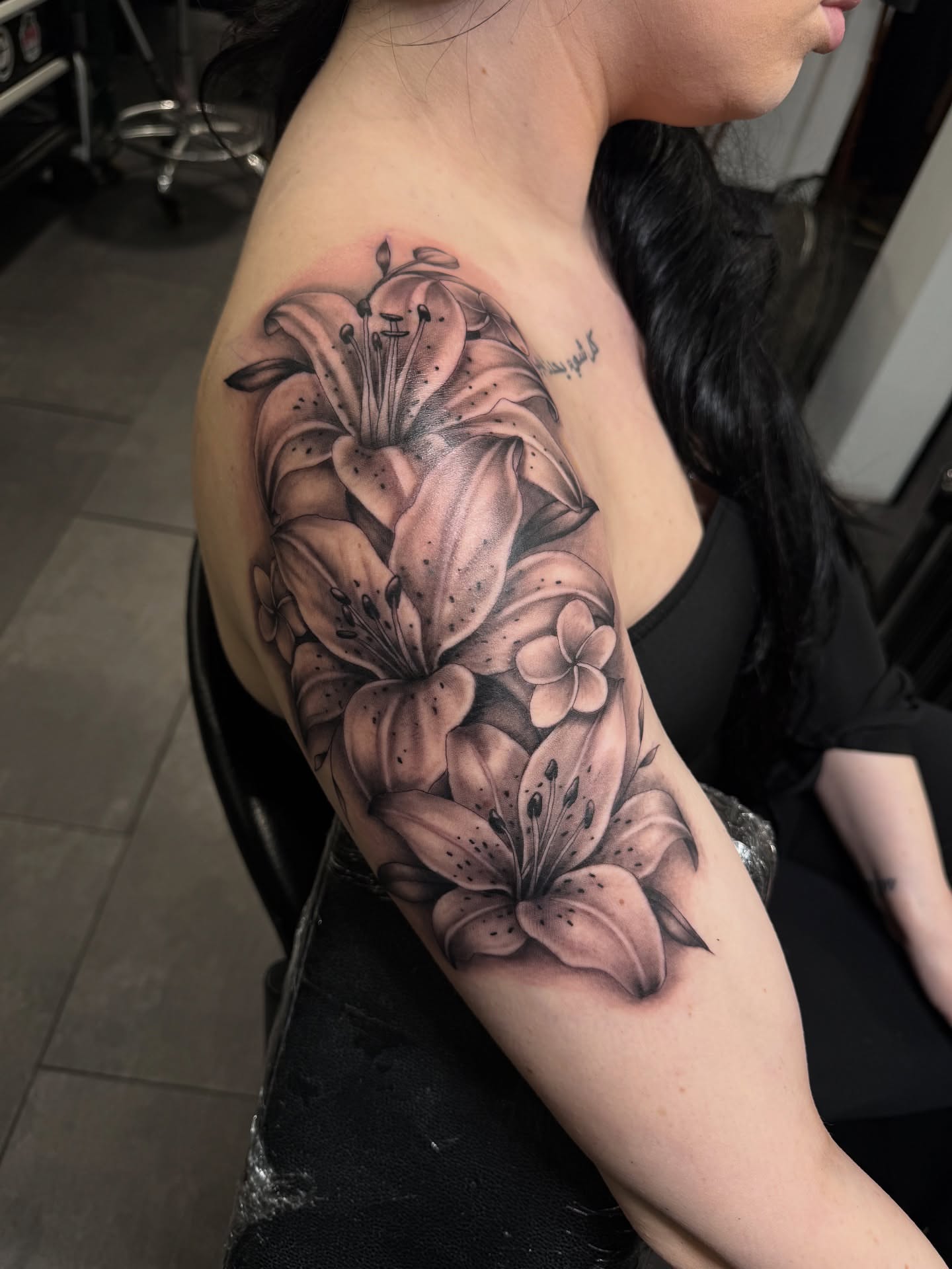 Lilies realism tattoo on the upper arm by Eduardo Chaparro